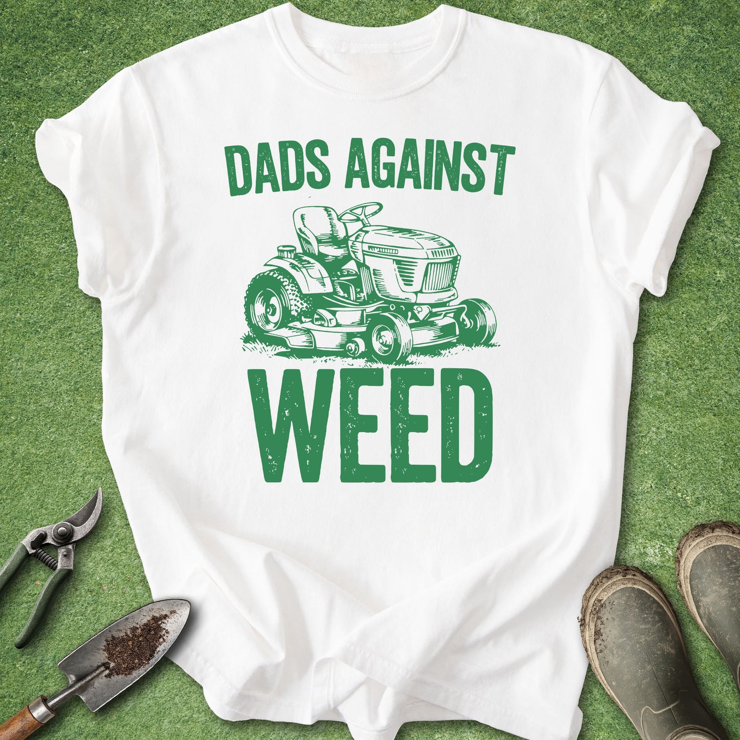 White t-shirt with green graphic and text 'Dads Against Weed' on a grass background