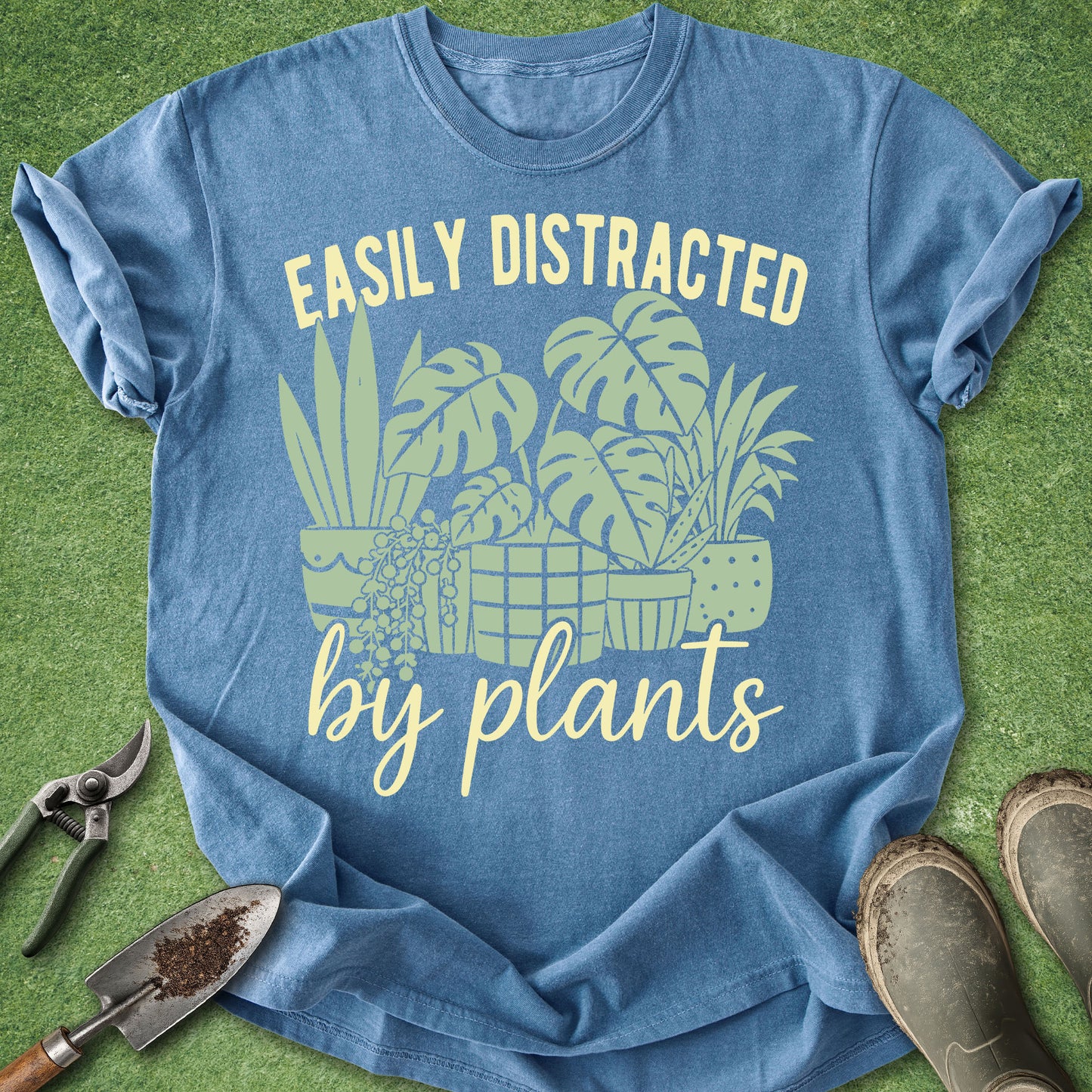 Blue t-shirt with plant-themed design and text on a grass background