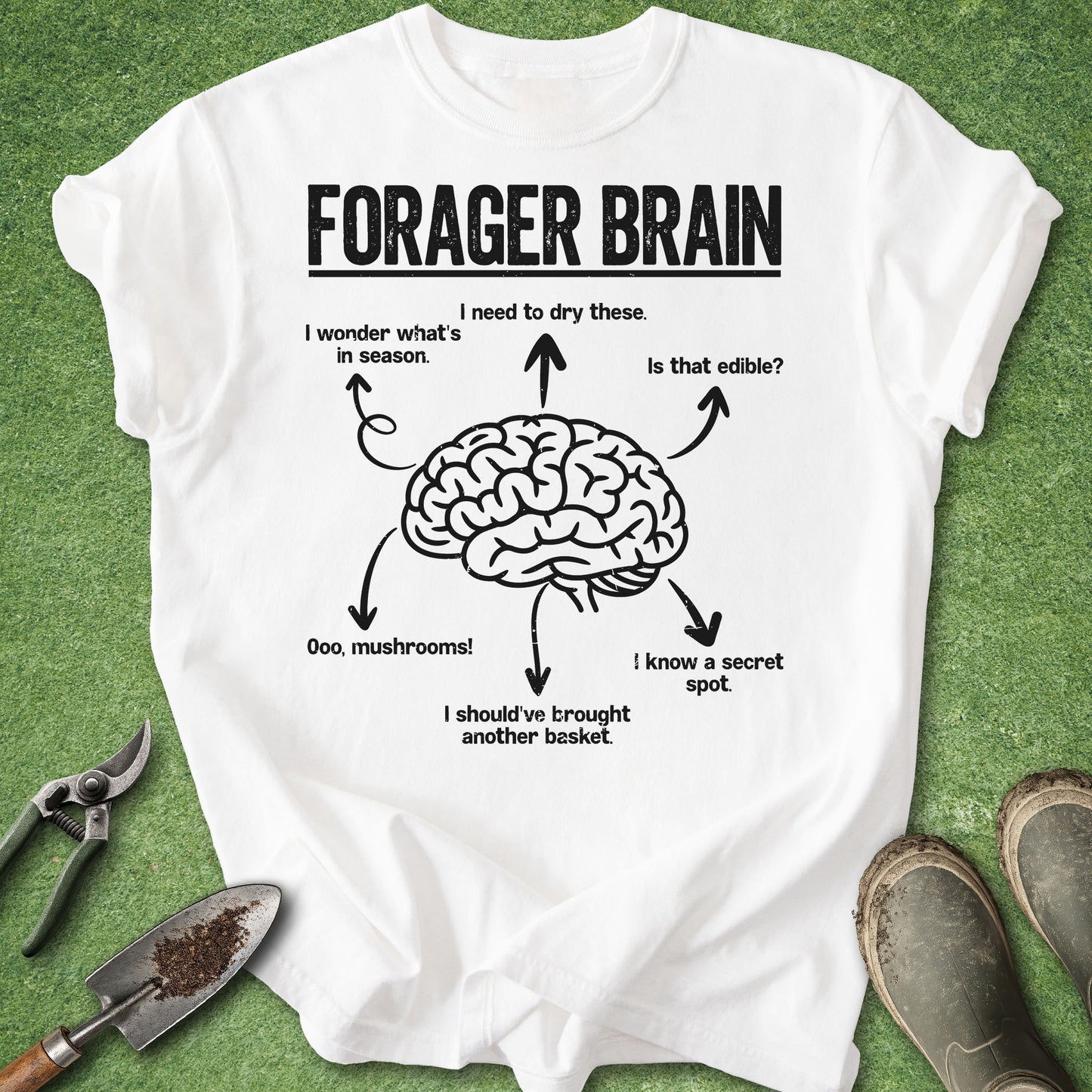 White t-shirt with a brain graphic and text on a green background with gardening tools.