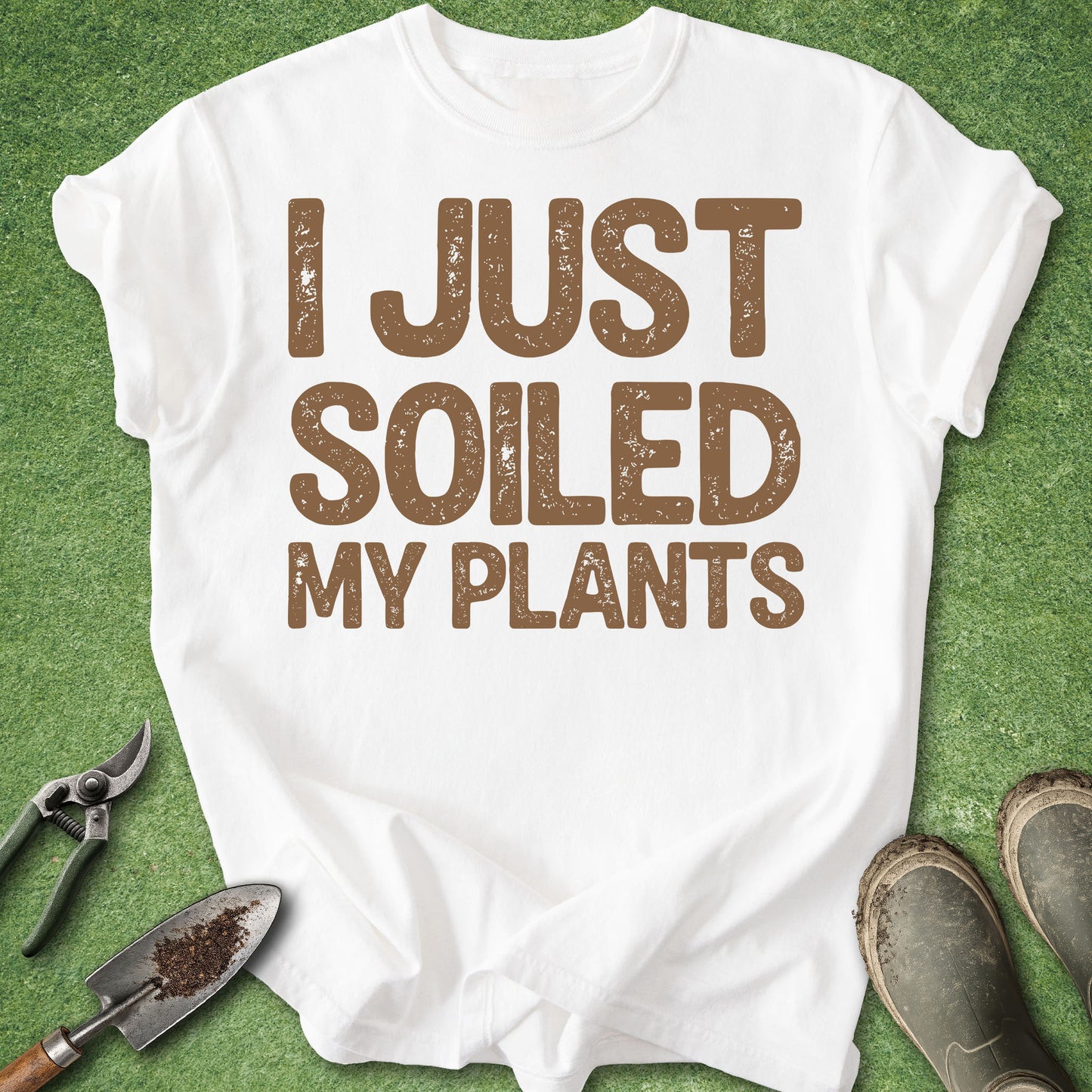 White t-shirt with 'I Just Soiled My Plants' text on a green background with gardening tools.