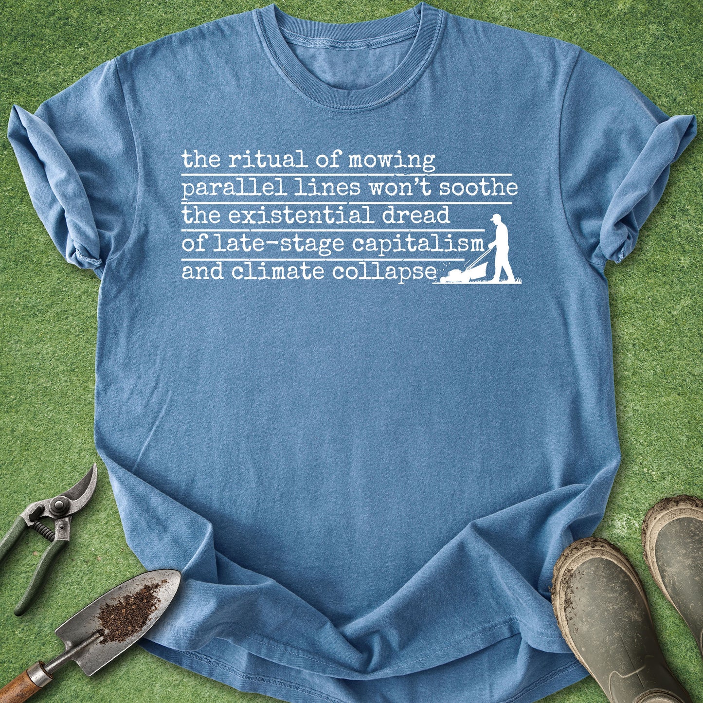 Blue t-shirt with text and graphic on grass with gardening tools