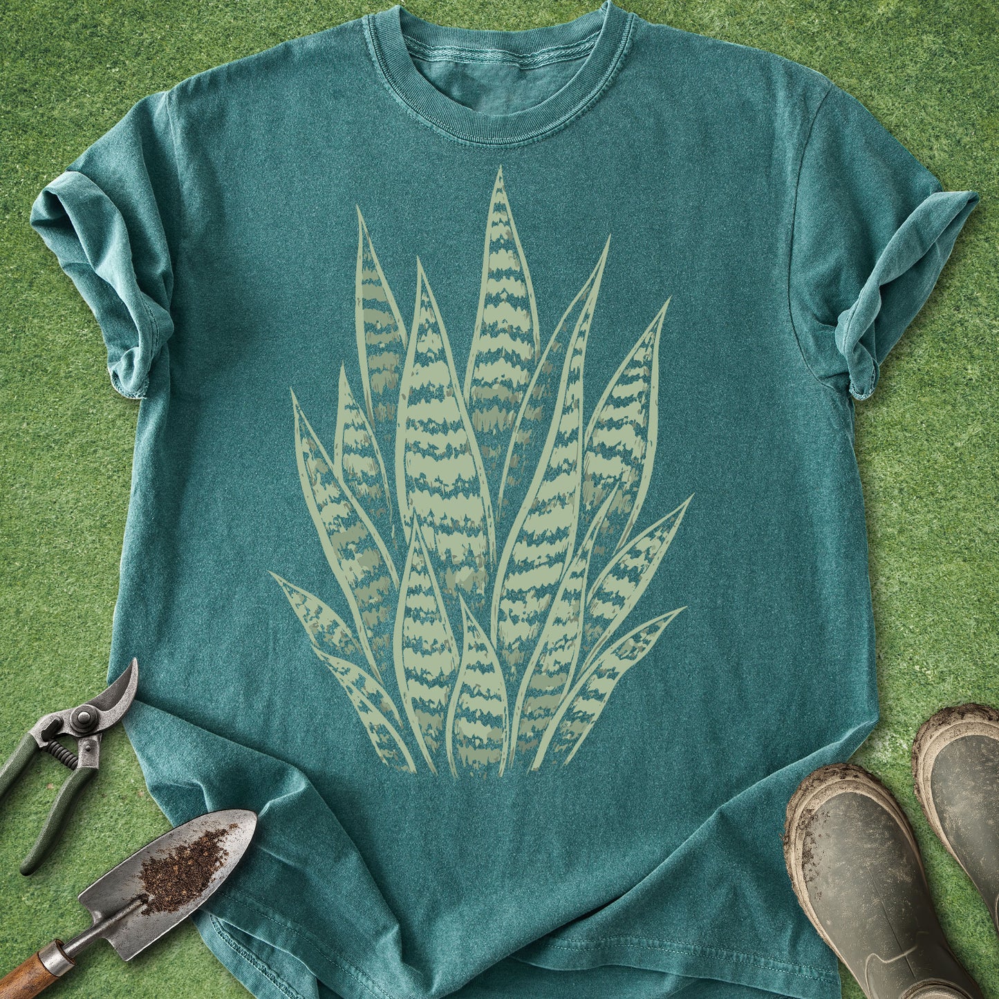 Teal t-shirt with a plant design on a grassy background