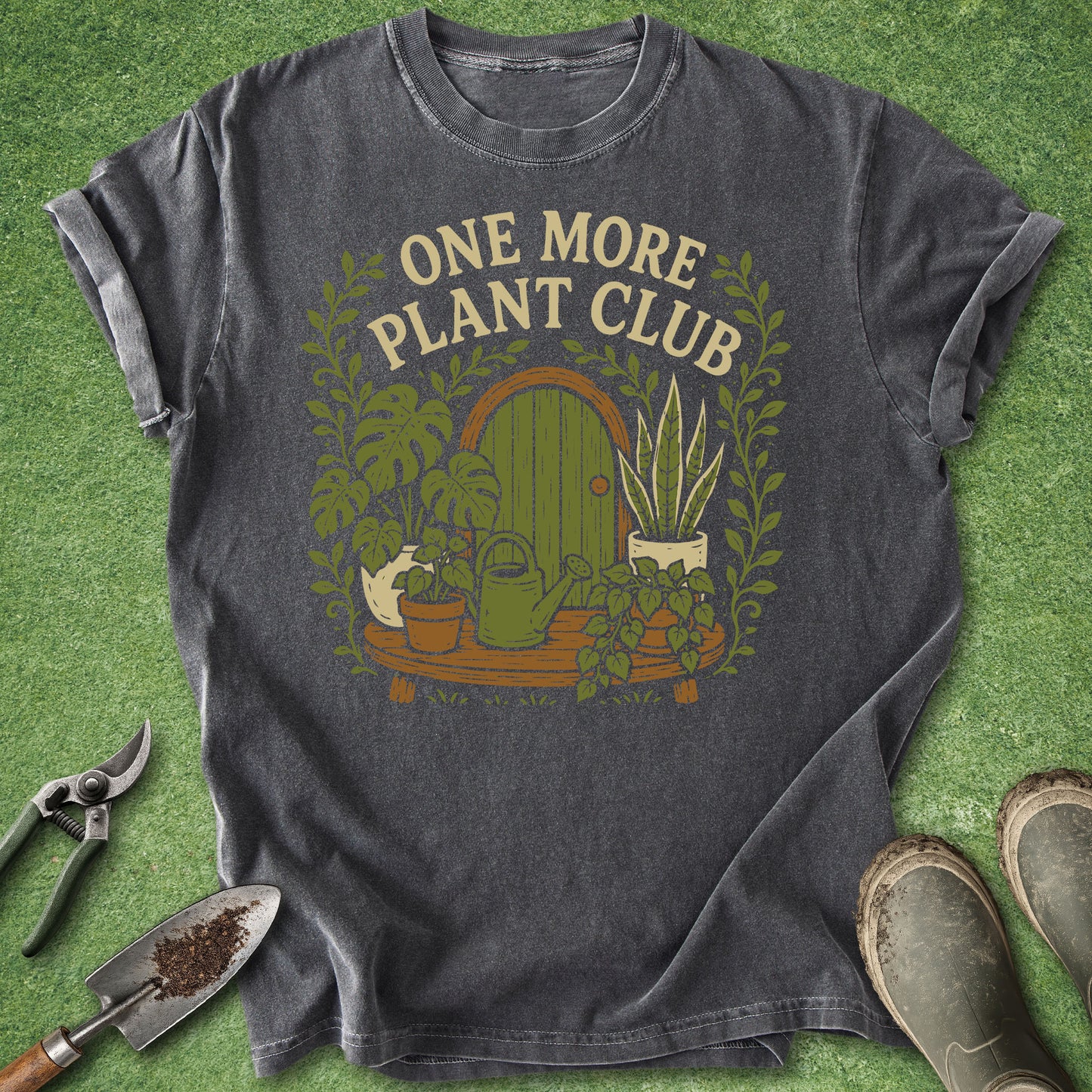 Vintage-inspired "One More Plant Club" design featuring a collection of houseplants, a watering can, and a whimsical garden door printed on a Comfort Colors 1717 plant lover t-shirt.