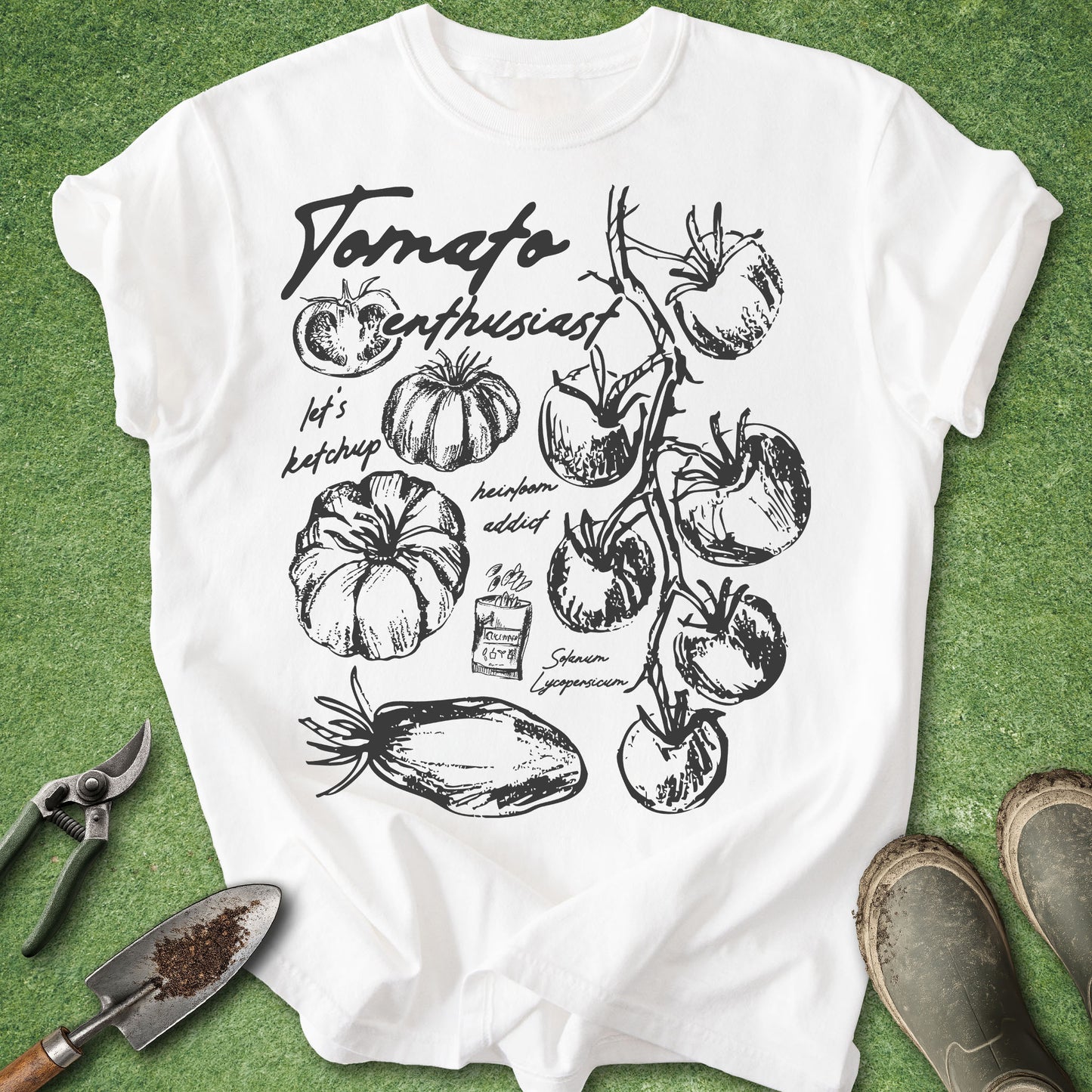 White t-shirt with black tomato illustration and text on a green grass background