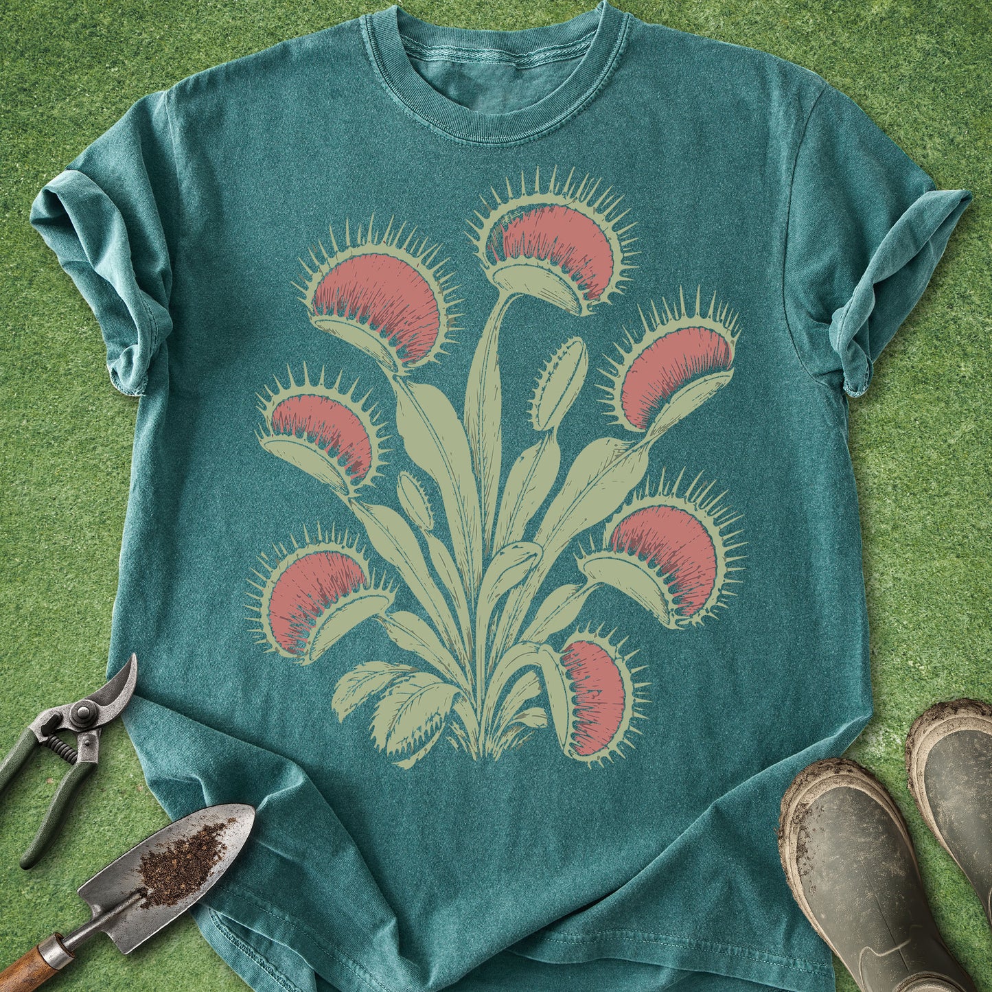 Teal t-shirt with Venus flytrap design on a grassy background