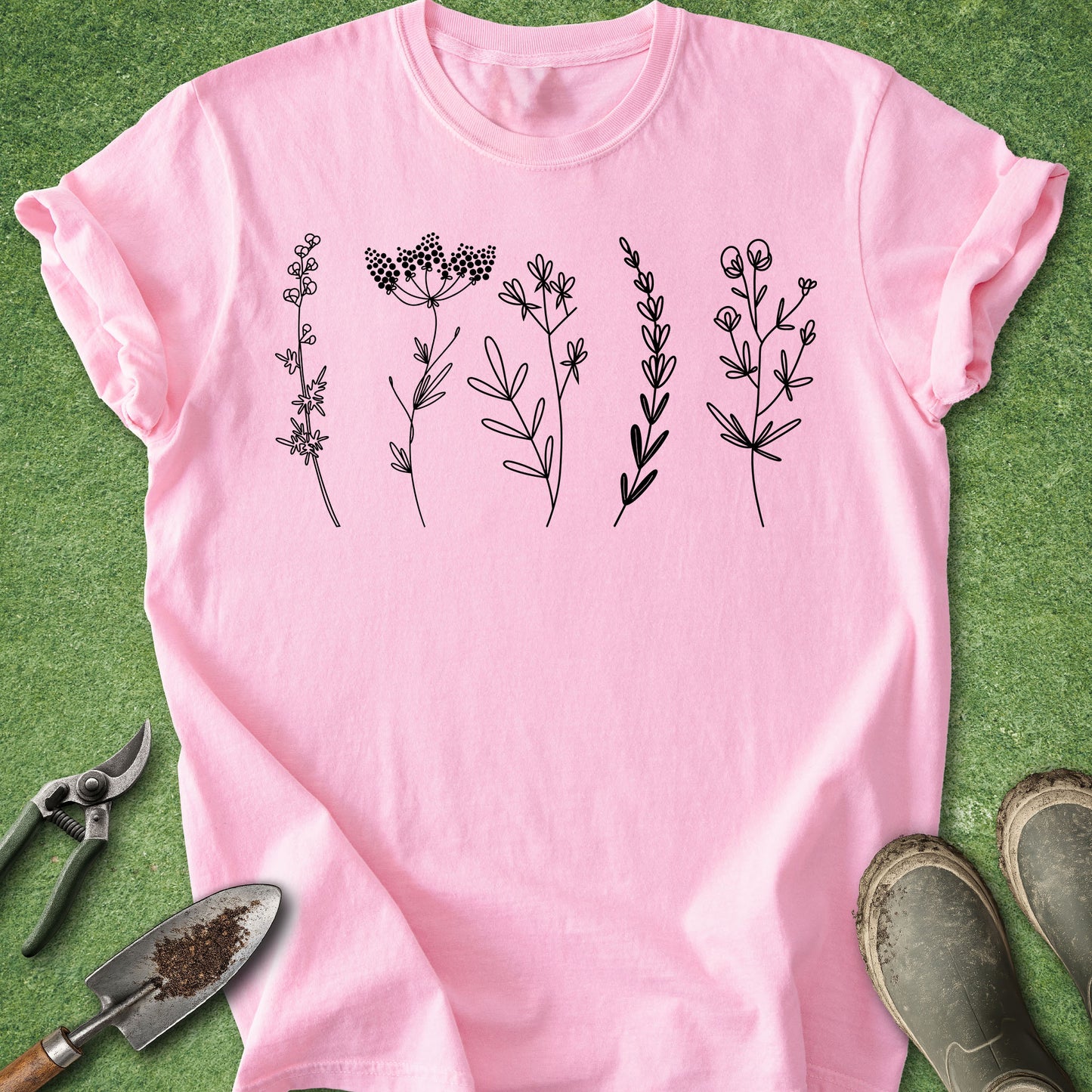Pink t-shirt with black floral designs on a green grass background
