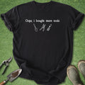 Black t-shirt with 'Oops, I bought more tools' text and tool graphics on a green grass background.
