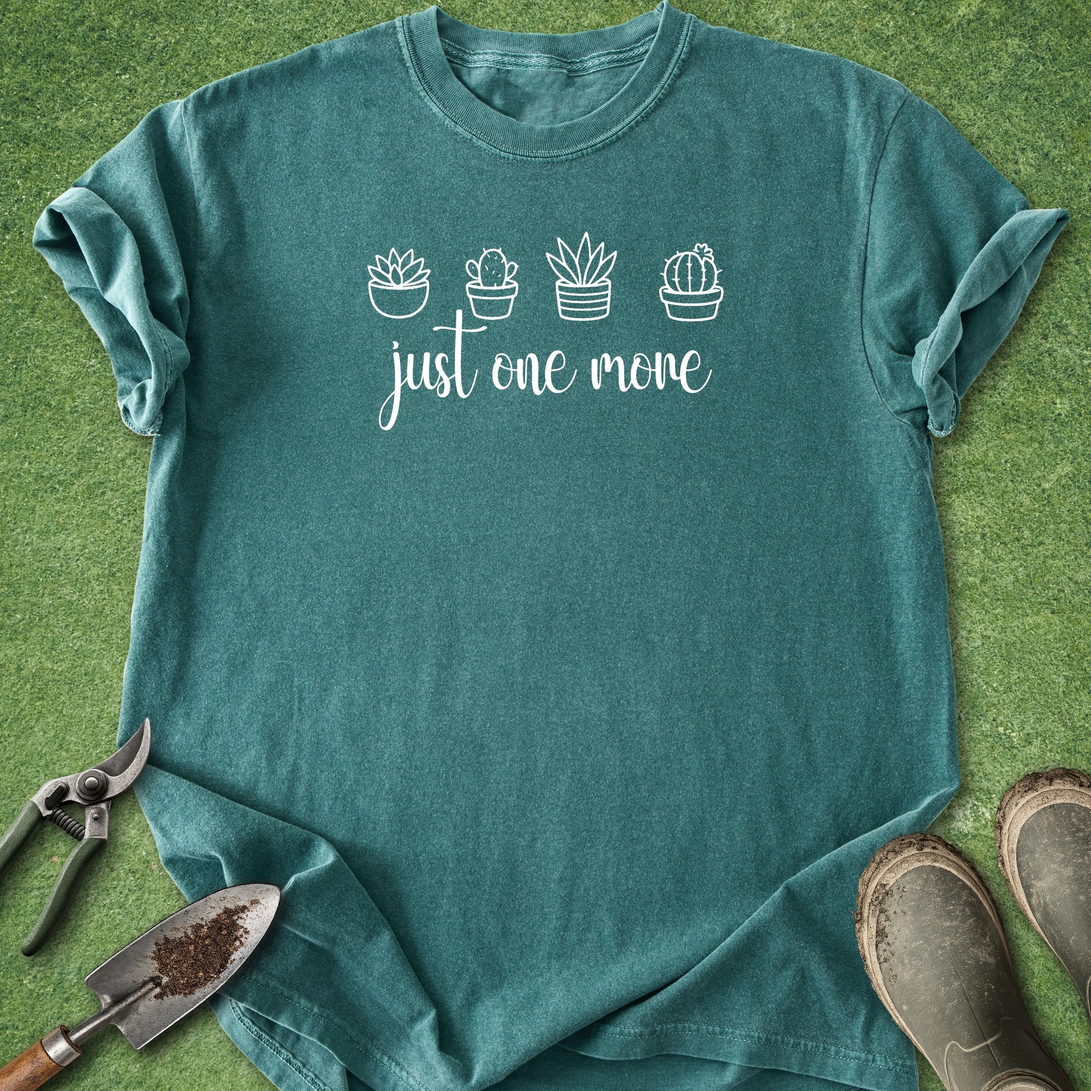 Teal t-shirt with cactus design and text on a grass background