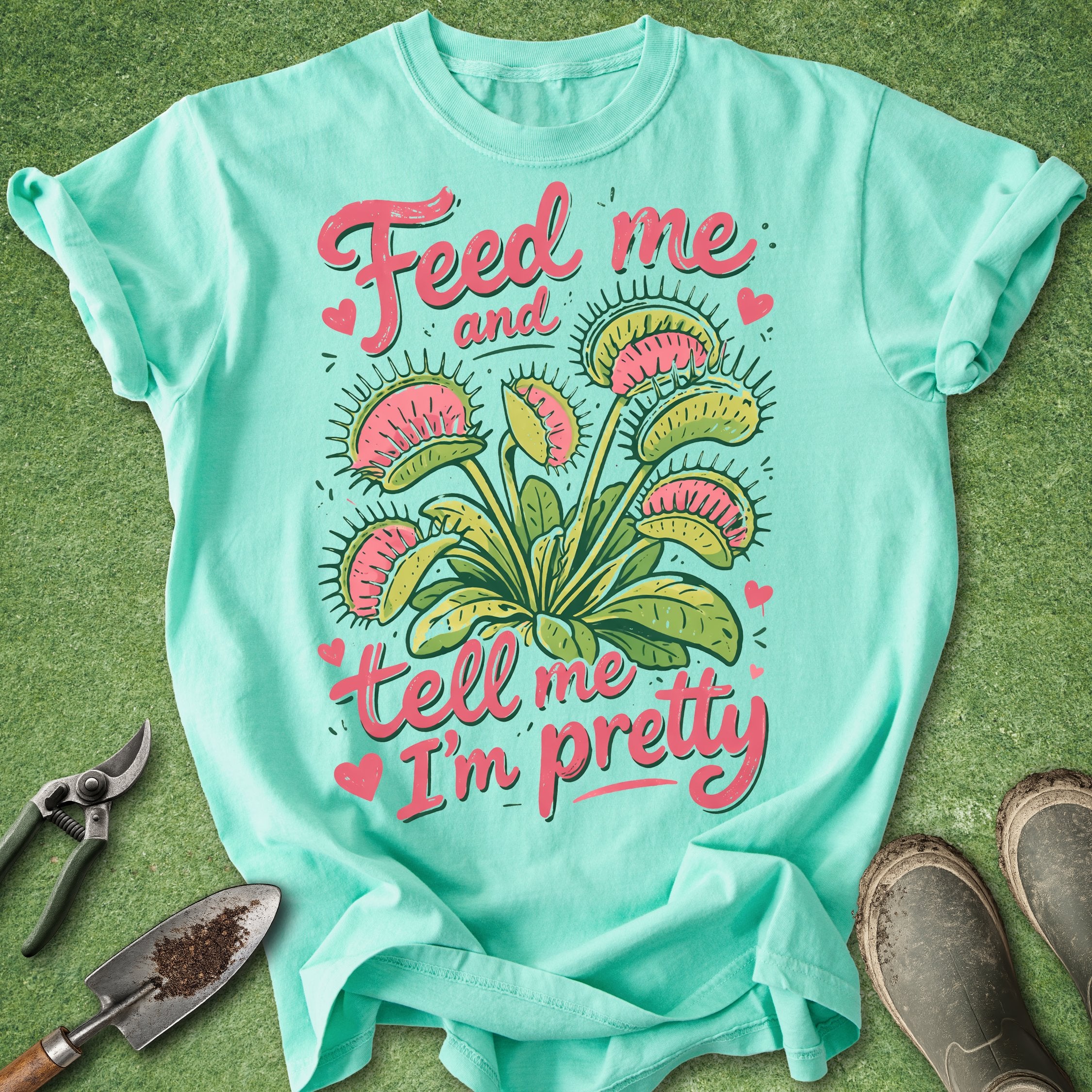 Mint green t-shirt with floral design and text on a grass background