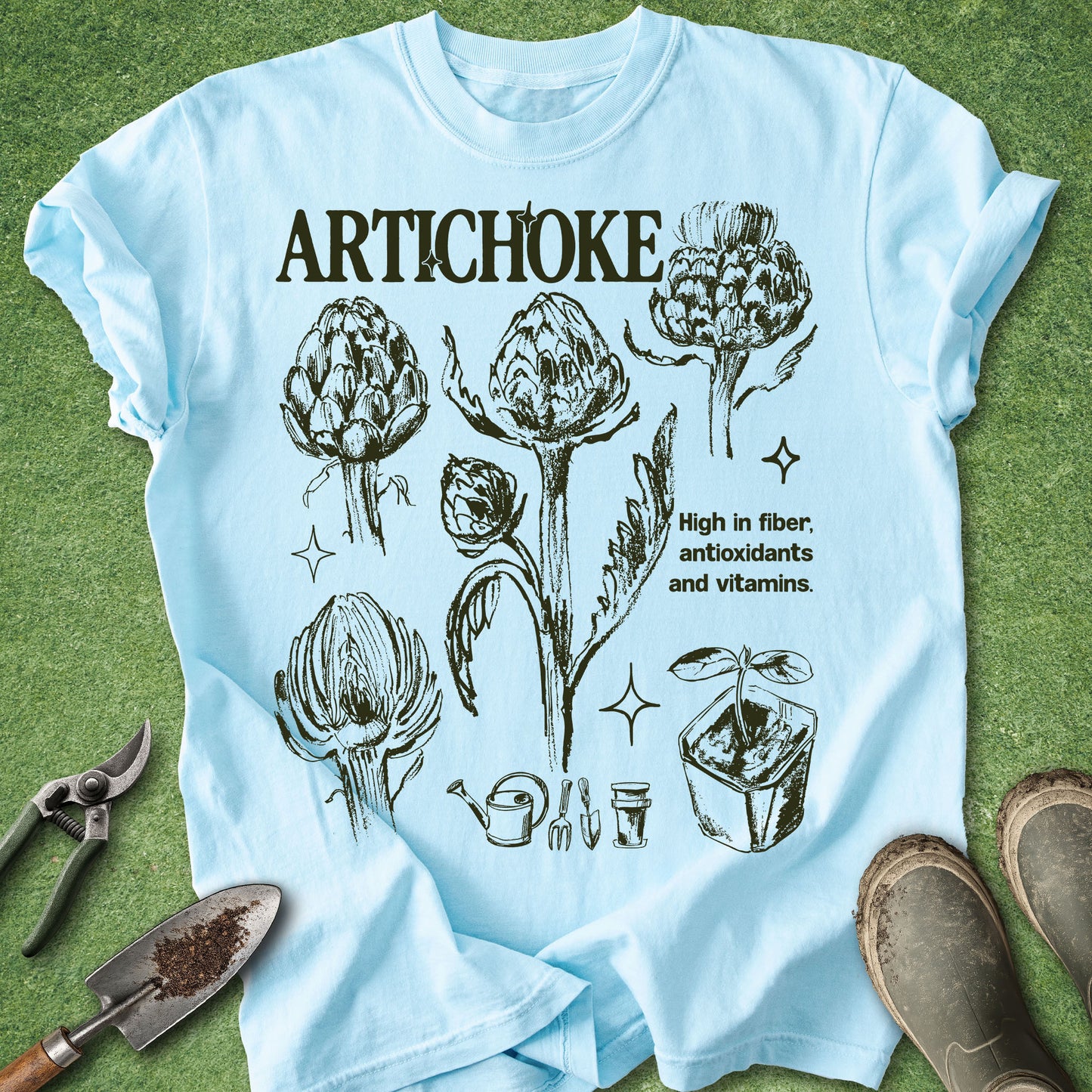 Chambray Comfort Colors t-shirt featuring vintage botanical illustrations of artichokes in different growth stages with gardening icons and educational text in a natural history inspired design.