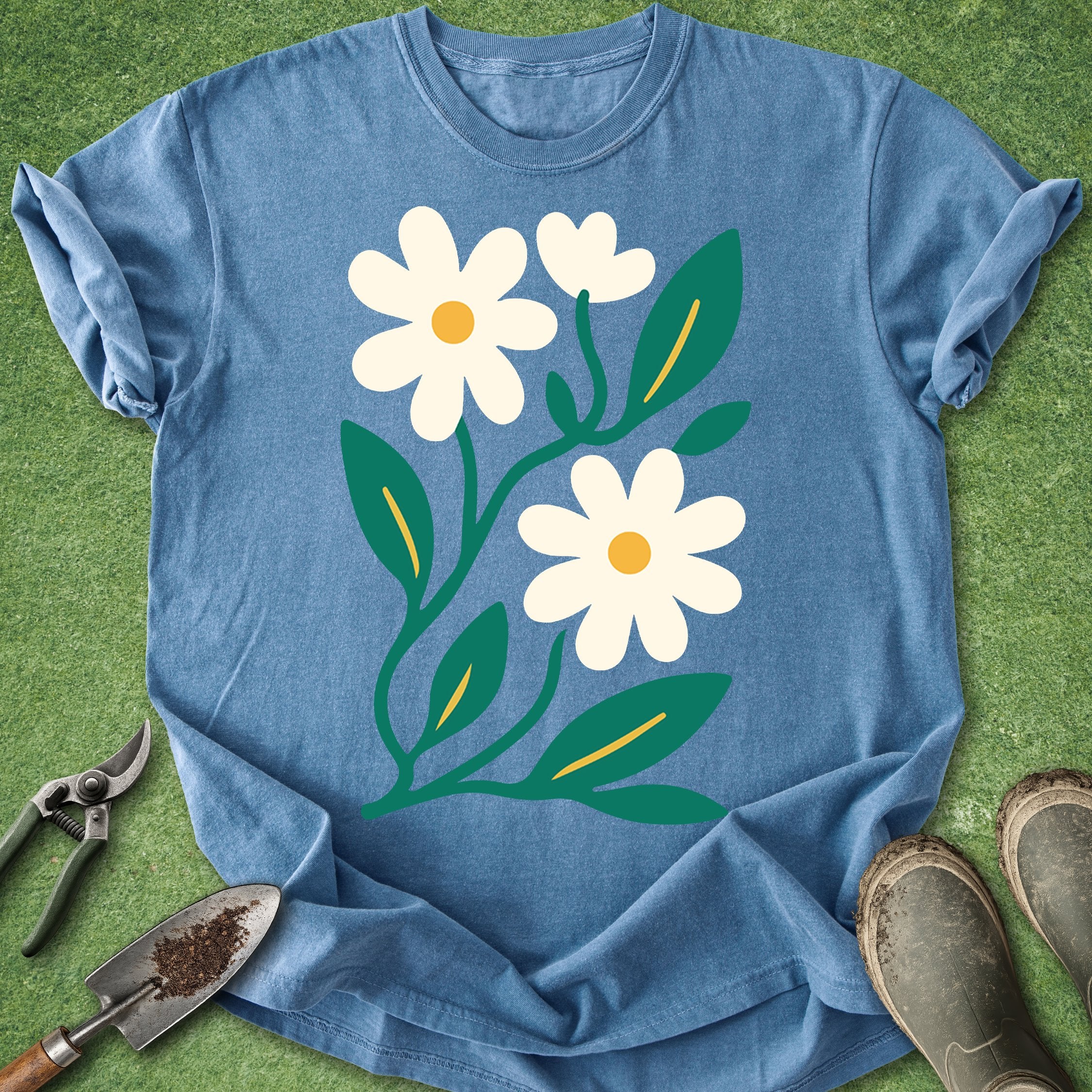 Blue t-shirt with white flowers and green leaves on a grass background