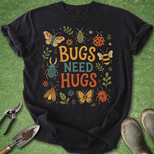 Black t-shirt with colorful retro insect illustrations including butterflies, beetles, bees and ladybugs surrounding the phrase Bugs Need Hugs.