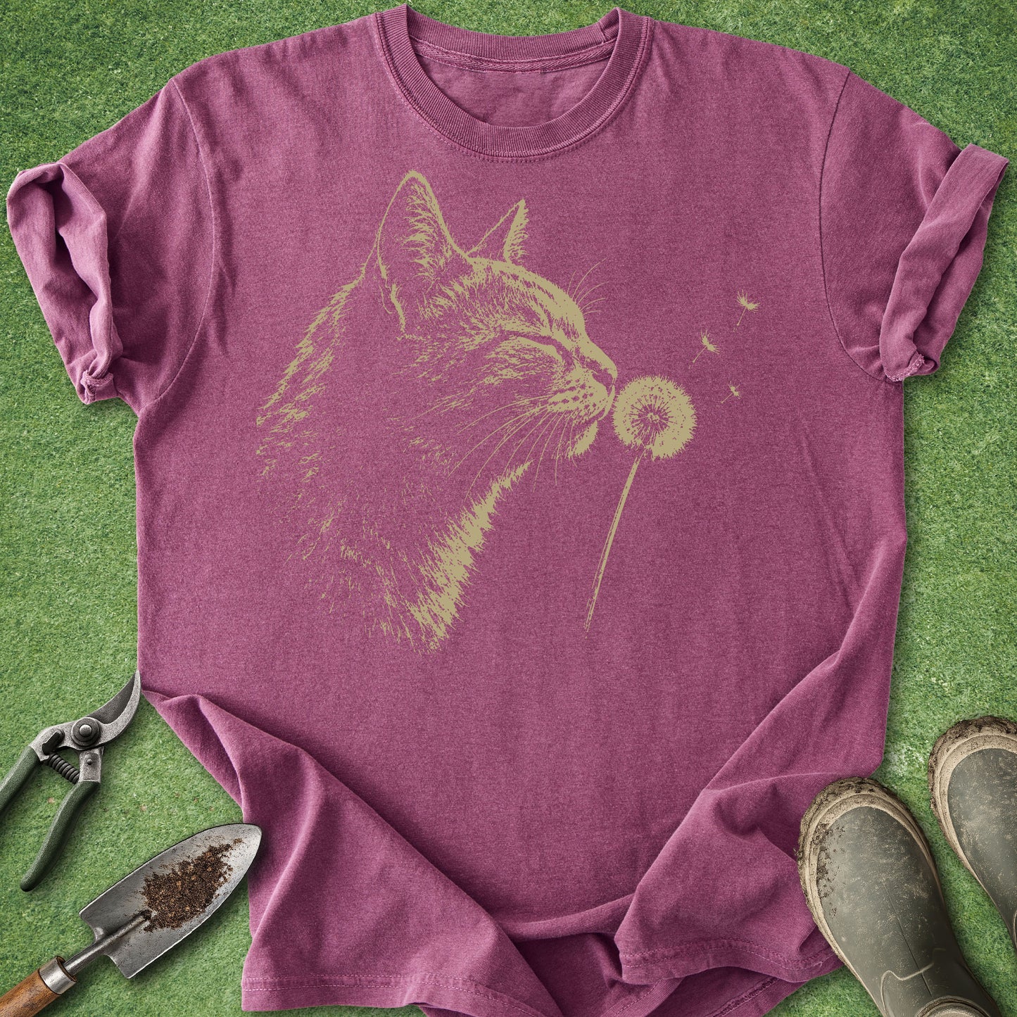 Purple t-shirt with a cat blowing dandelion design on a grass background