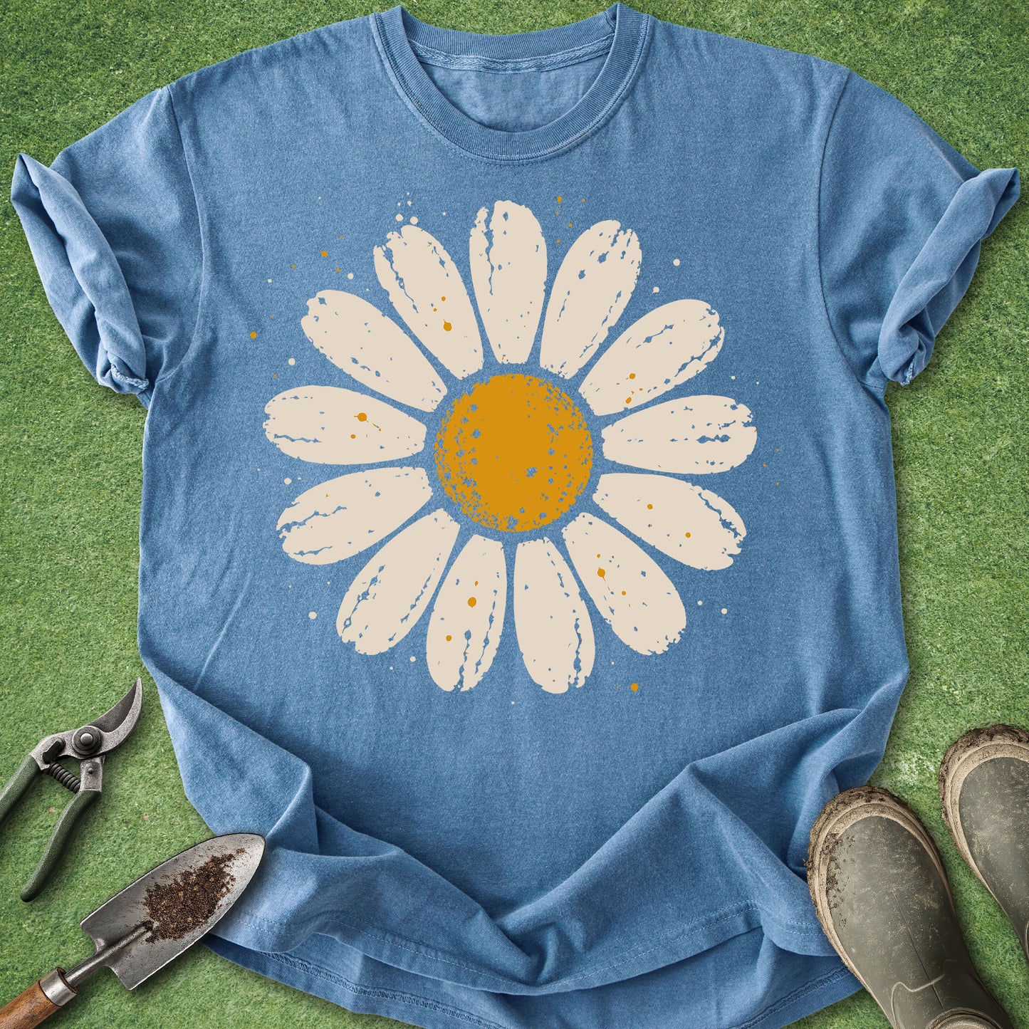 Blue jean colored t-shirt featuring a large distressed cream and golden yellow daisy flower with subtle paint splatter details.
