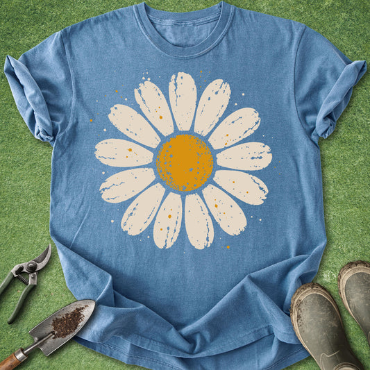 Blue jean colored t-shirt featuring a large distressed cream and golden yellow daisy flower with subtle paint splatter details.
