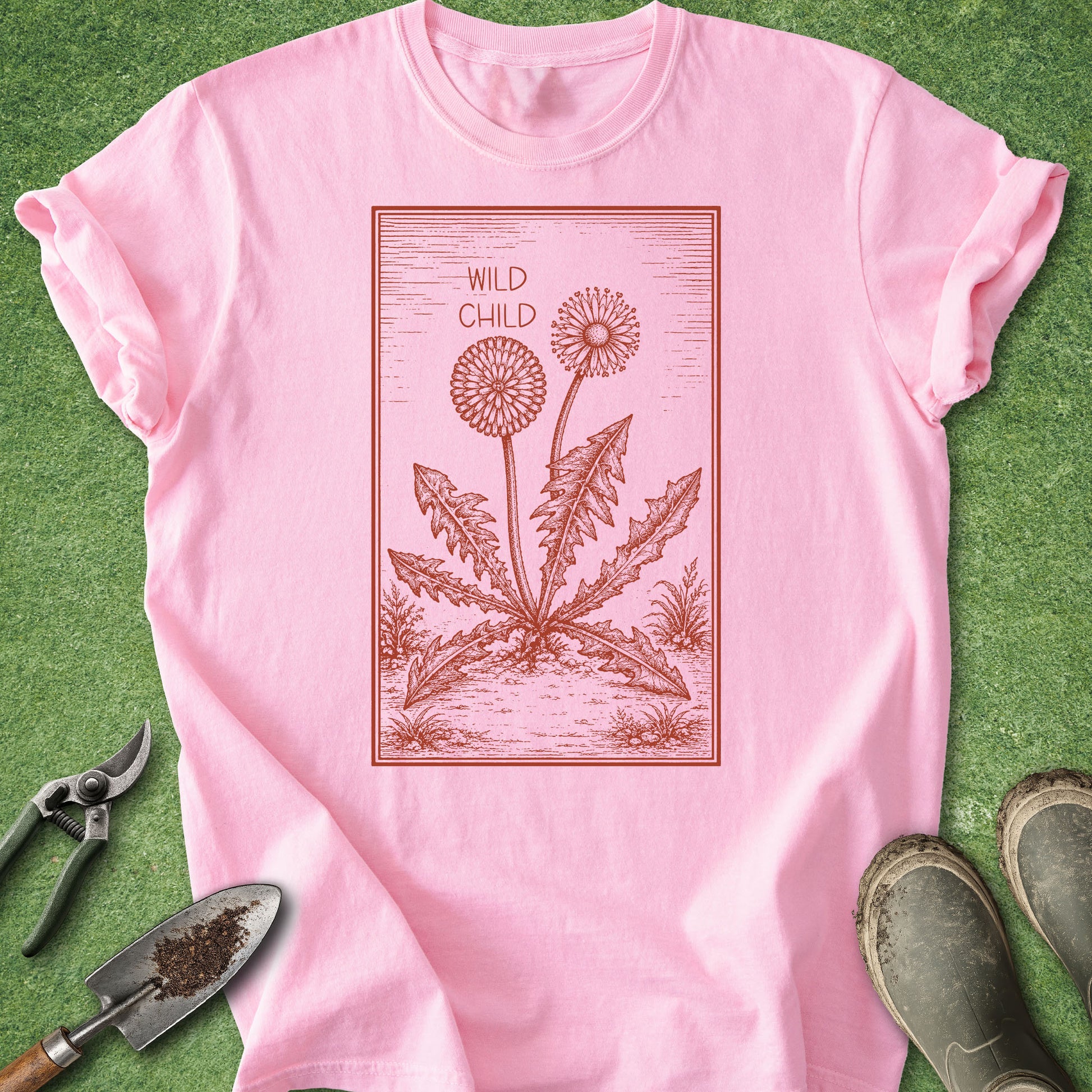 Pink t-shirt with dandelion graphic and 'Wild Child' text on a green background