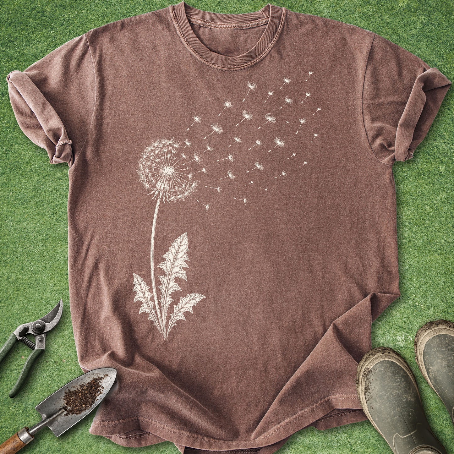Brown t-shirt with dandelion graphic on a green grass background
