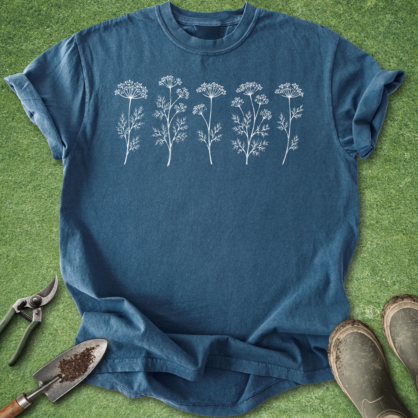 Blue t-shirt with white floral designs on a green grass background
