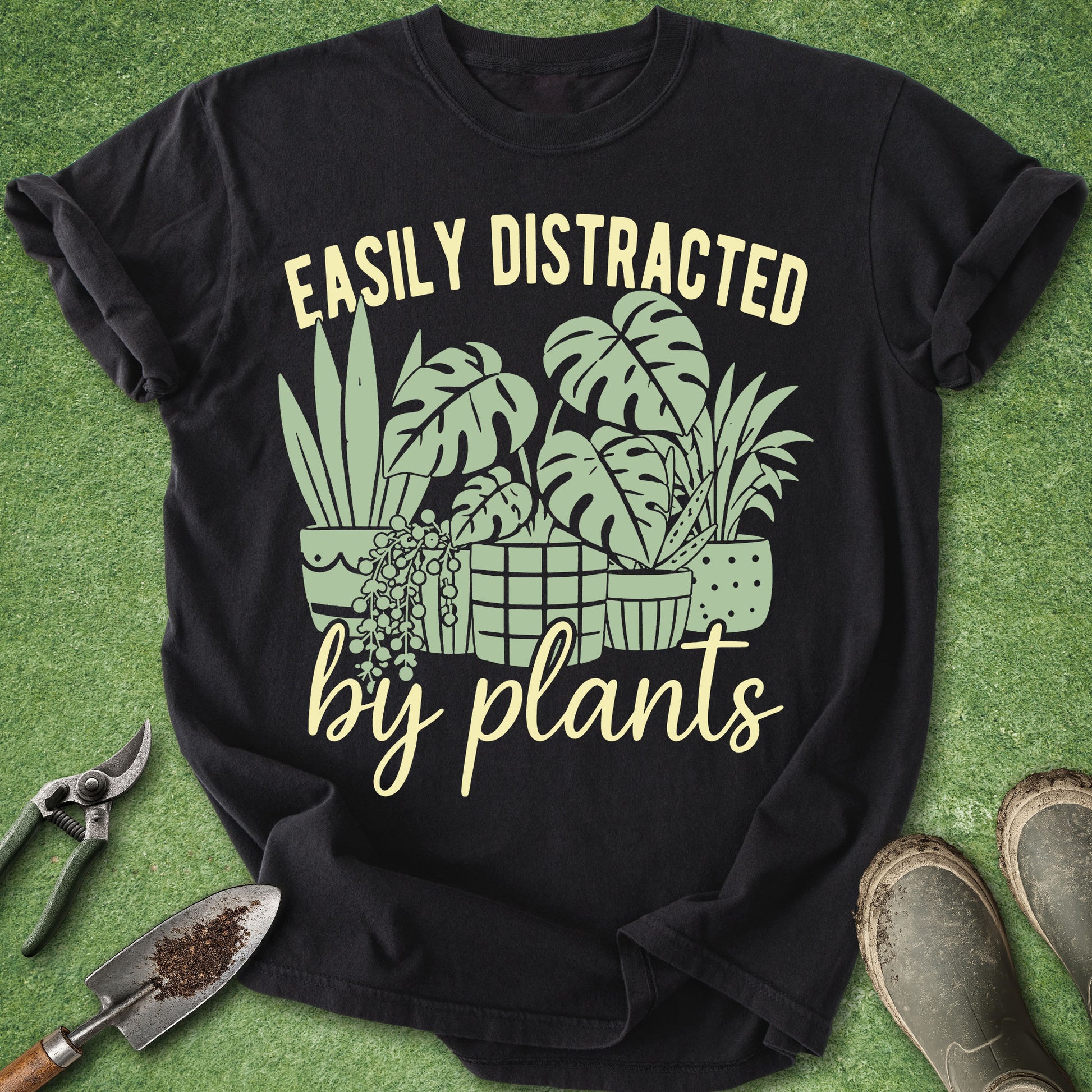 Black t-shirt with plant-themed design and text on a green grass background