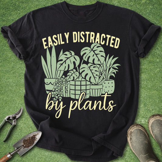 Black t-shirt with plant-themed design and text on a green grass background