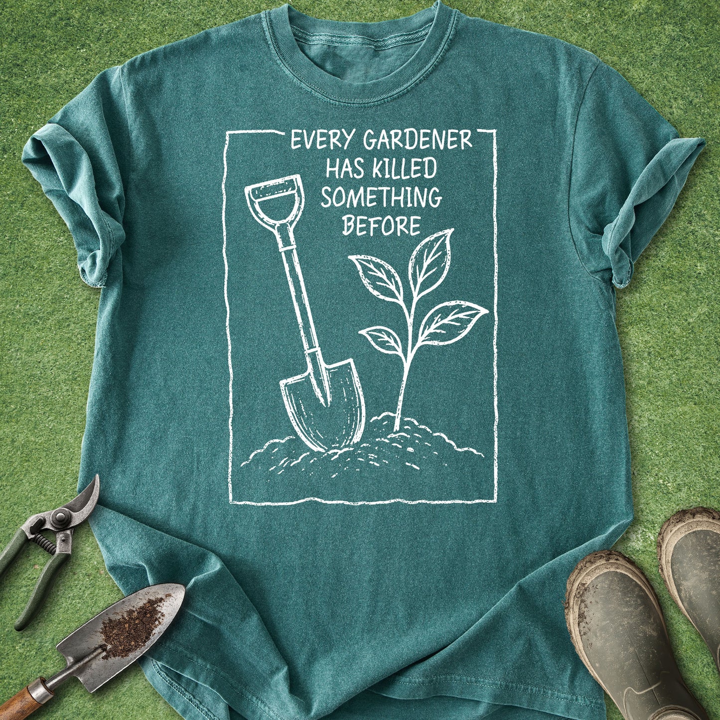 Teal t-shirt with gardening graphic and text on a grass background