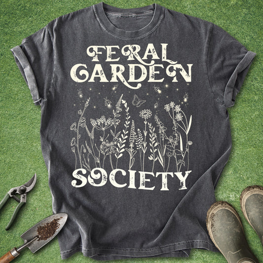 Vintage botanical gardening shirt featuring the words "Feral Garden Society" with delicate wildflowers, butterflies, and glowing fireflies on a dark charcoal background.