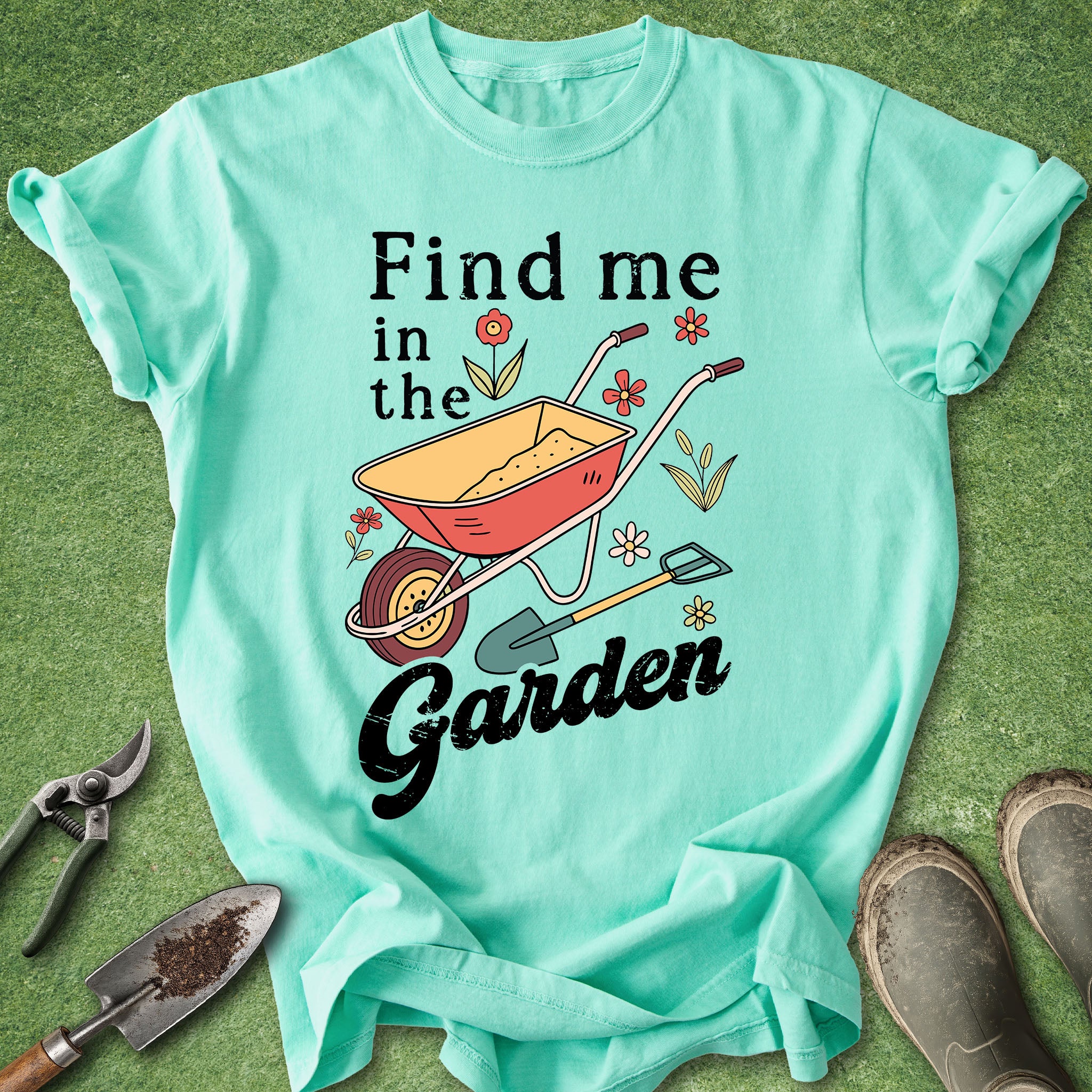 Mint green t-shirt with garden-themed design and text on a grass background
