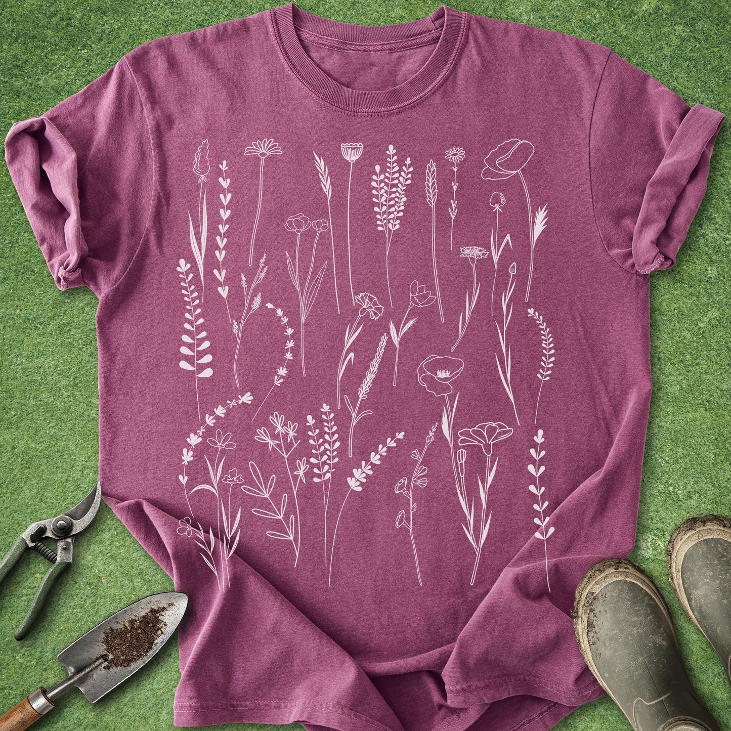 Purple t-shirt with white floral designs on a green grass background