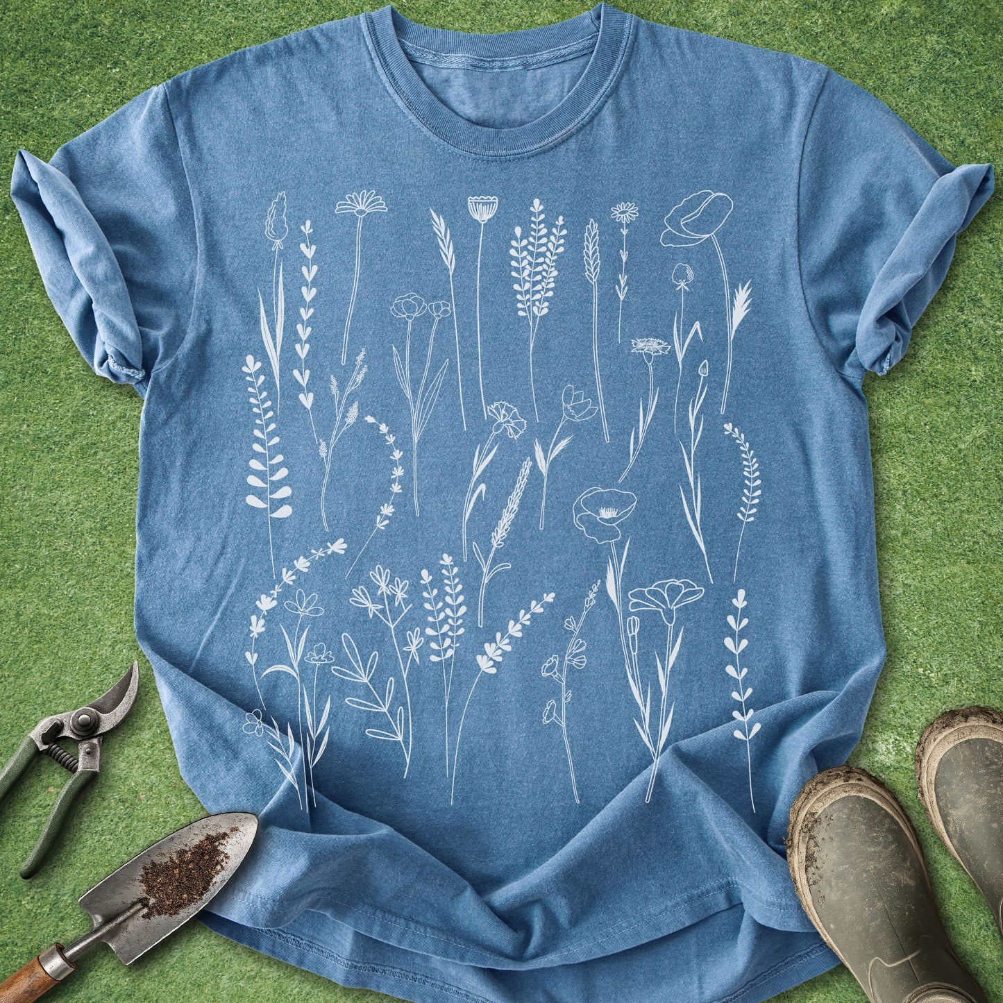 Blue t-shirt with white floral designs on a green grass background