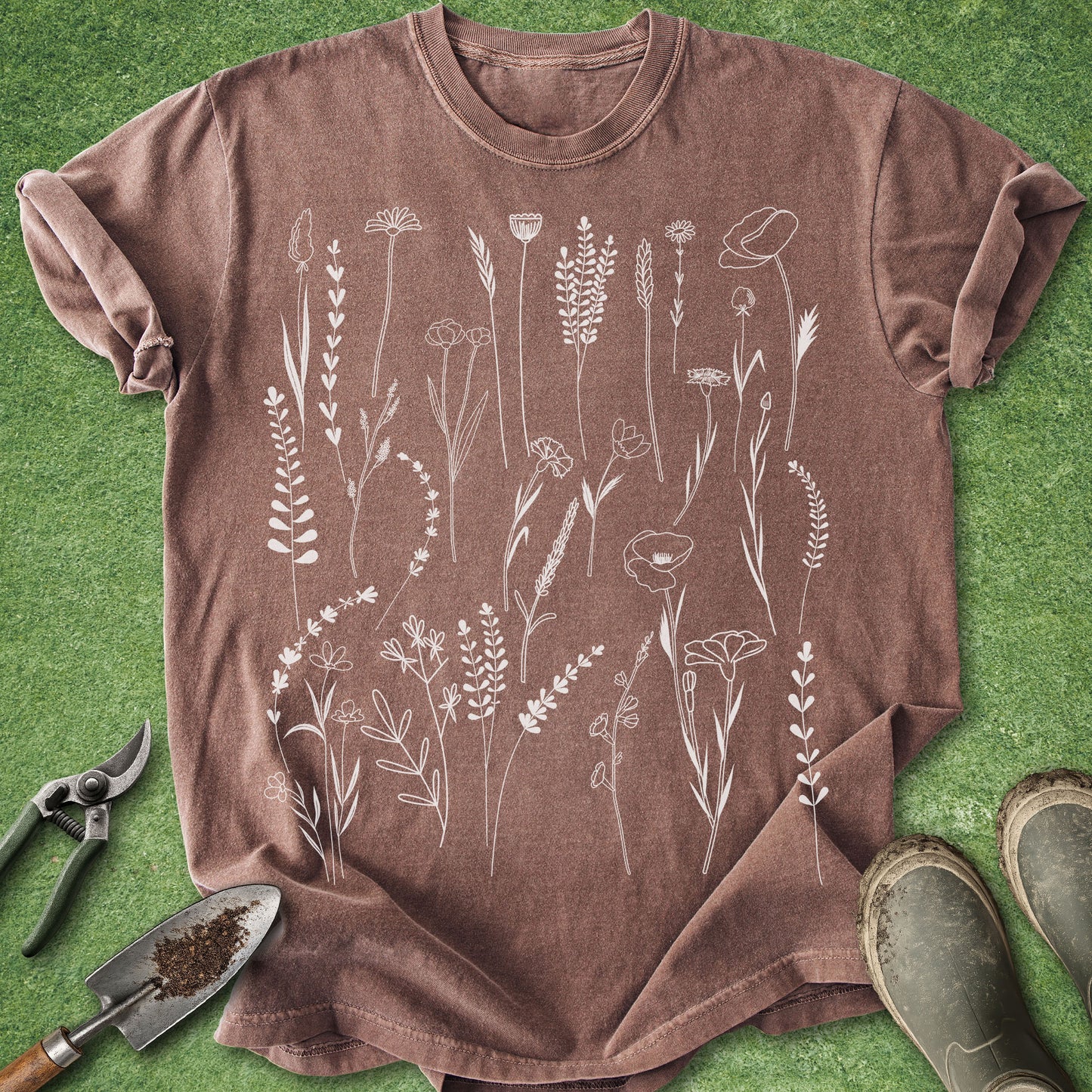 Brown t-shirt with white floral design on a green grass background