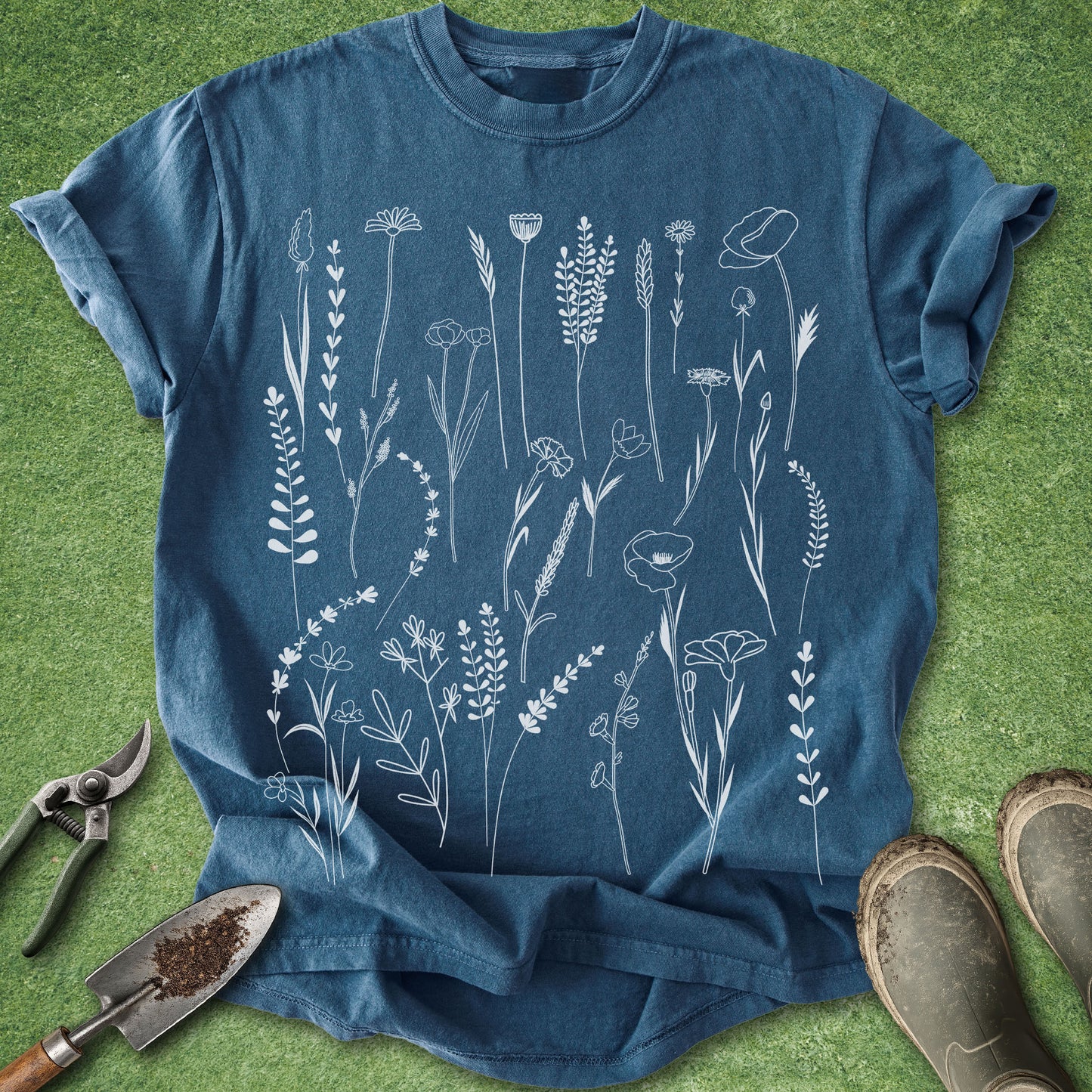 Blue t-shirt with white floral design on a green grass background