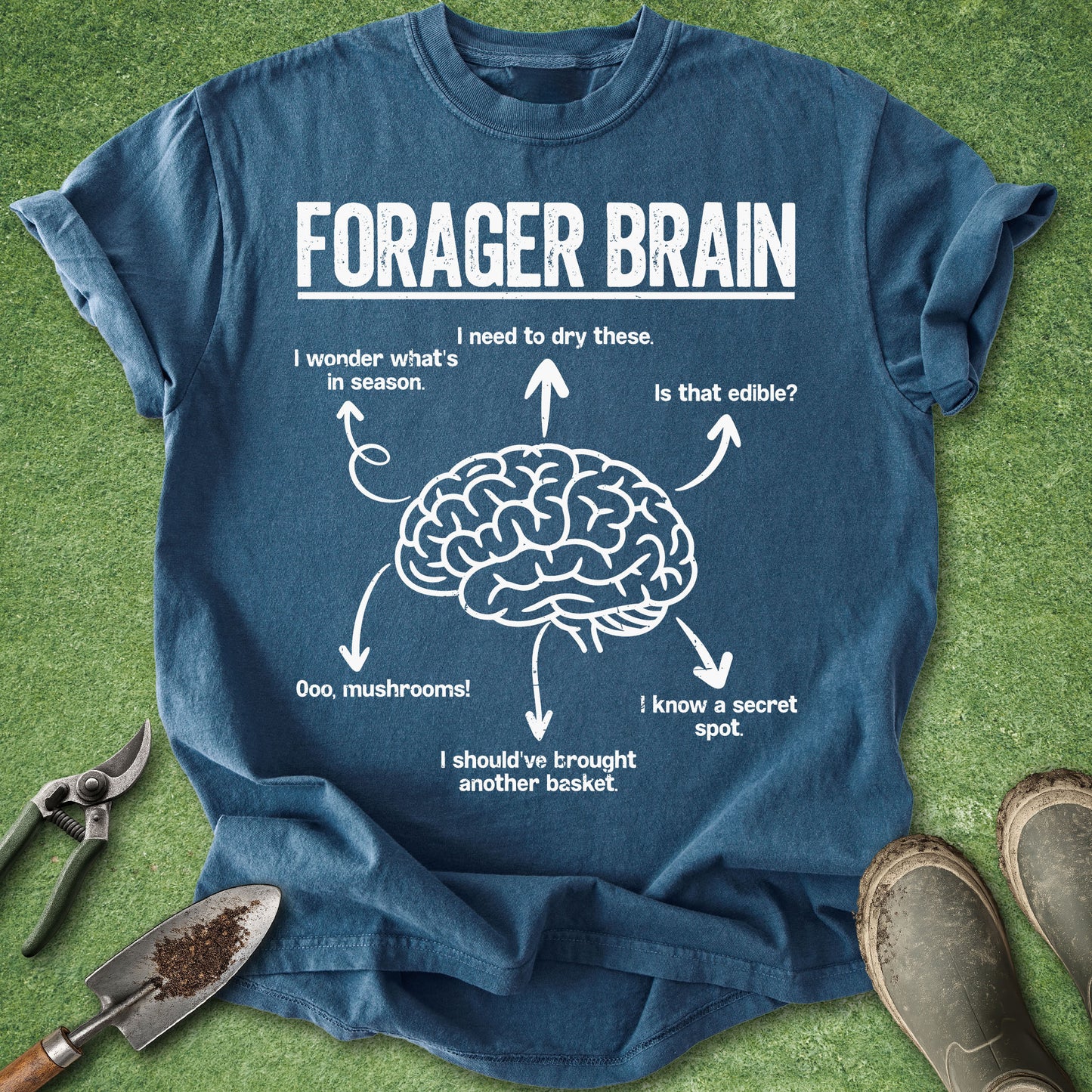 Midnight blue Comfort Colors t-shirt featuring a humorous Forager Brain graphic with a brain illustration surrounded by thoughts about mushrooms, edible plants, secret foraging spots, seasonal foods, and gathering baskets.