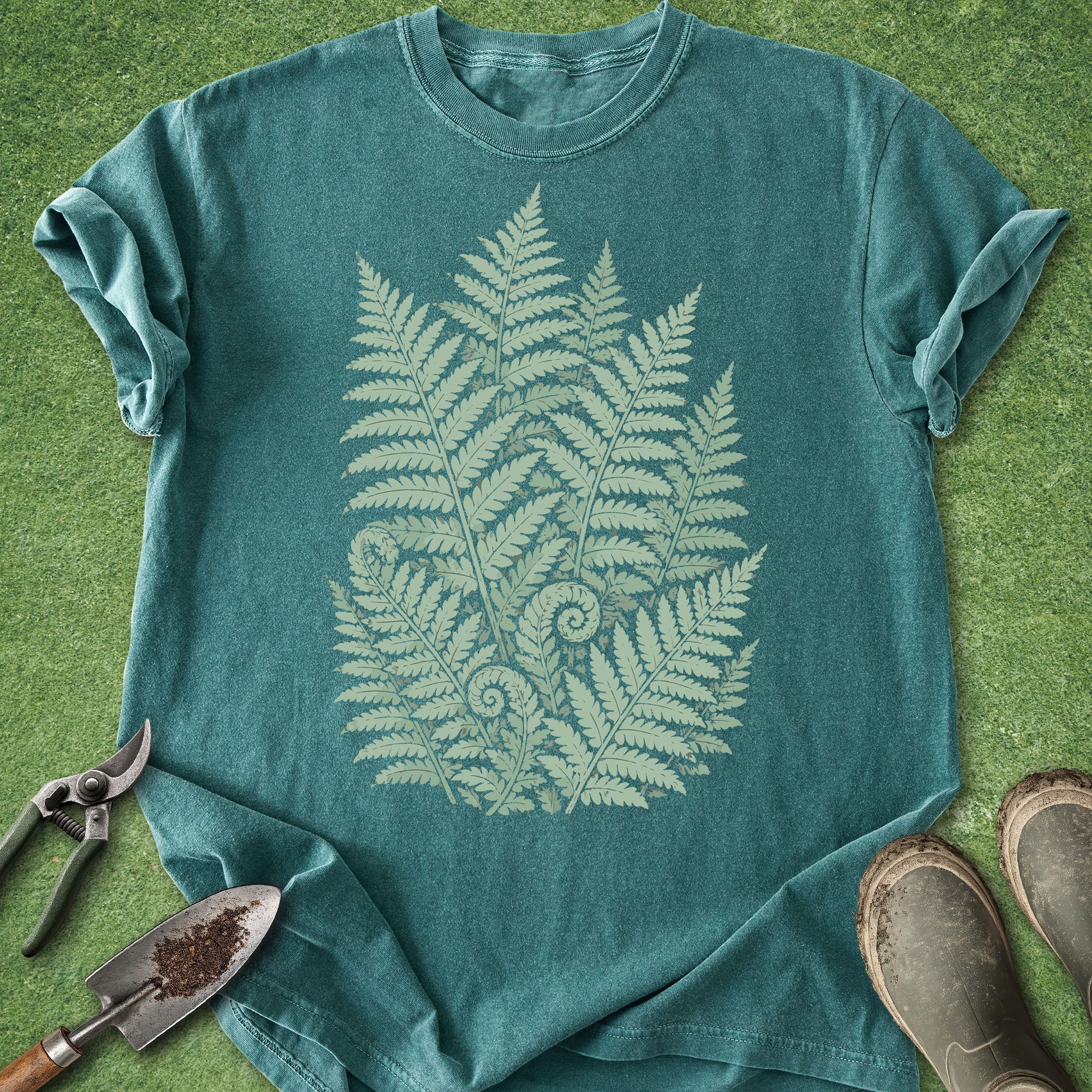 Teal t-shirt with fern design on a grassy background