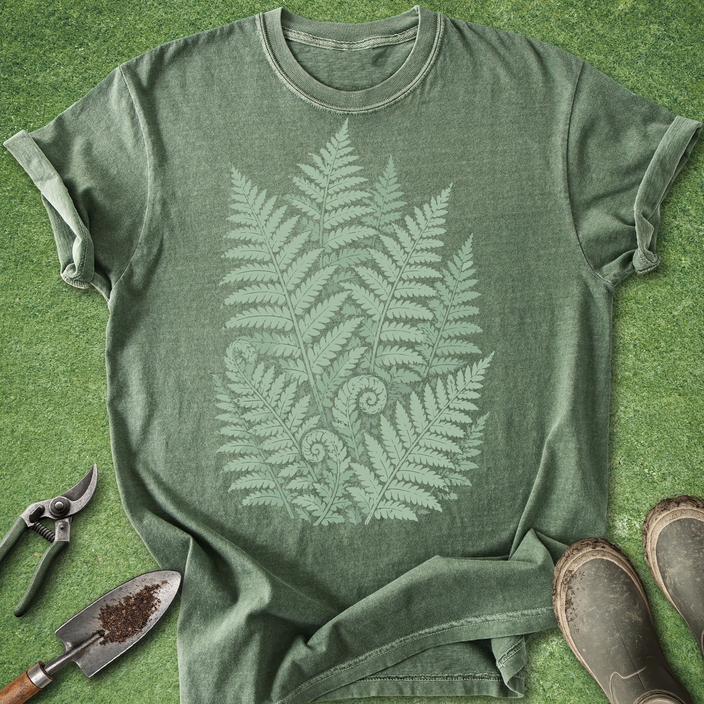 Green t-shirt with fern leaf design on a grassy background