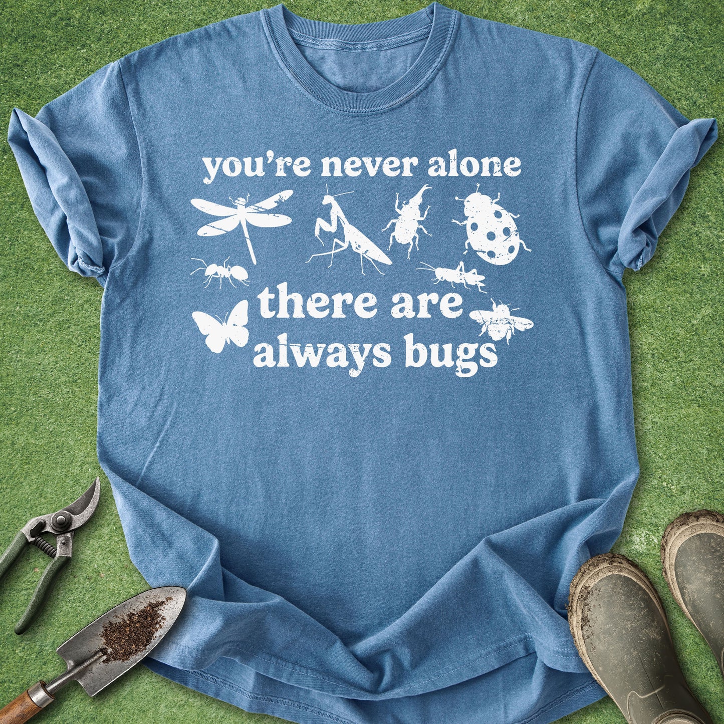 Blue t-shirt with white text and insect illustrations on a green grass background
