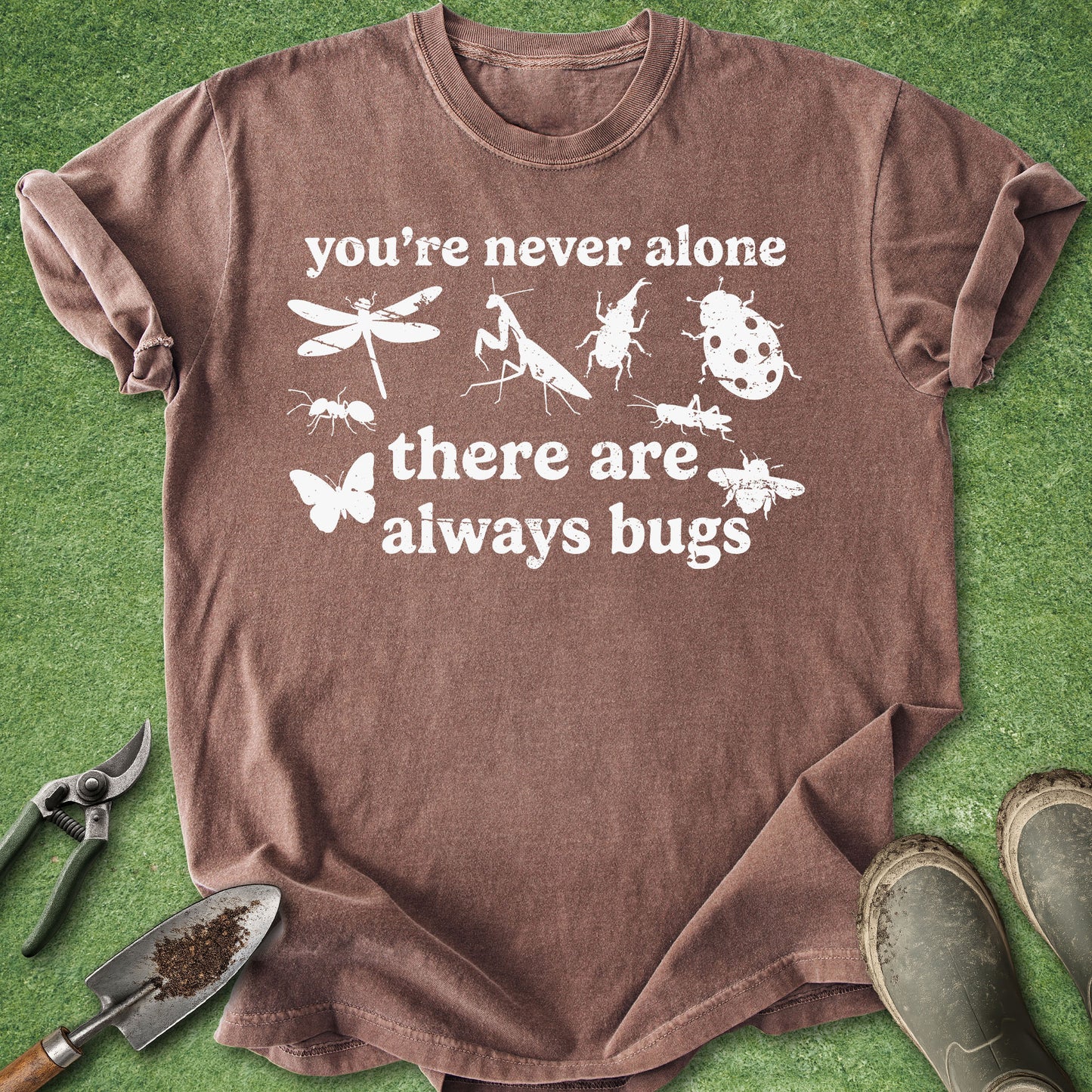 Brown t-shirt with insect illustrations and text on a green grass background