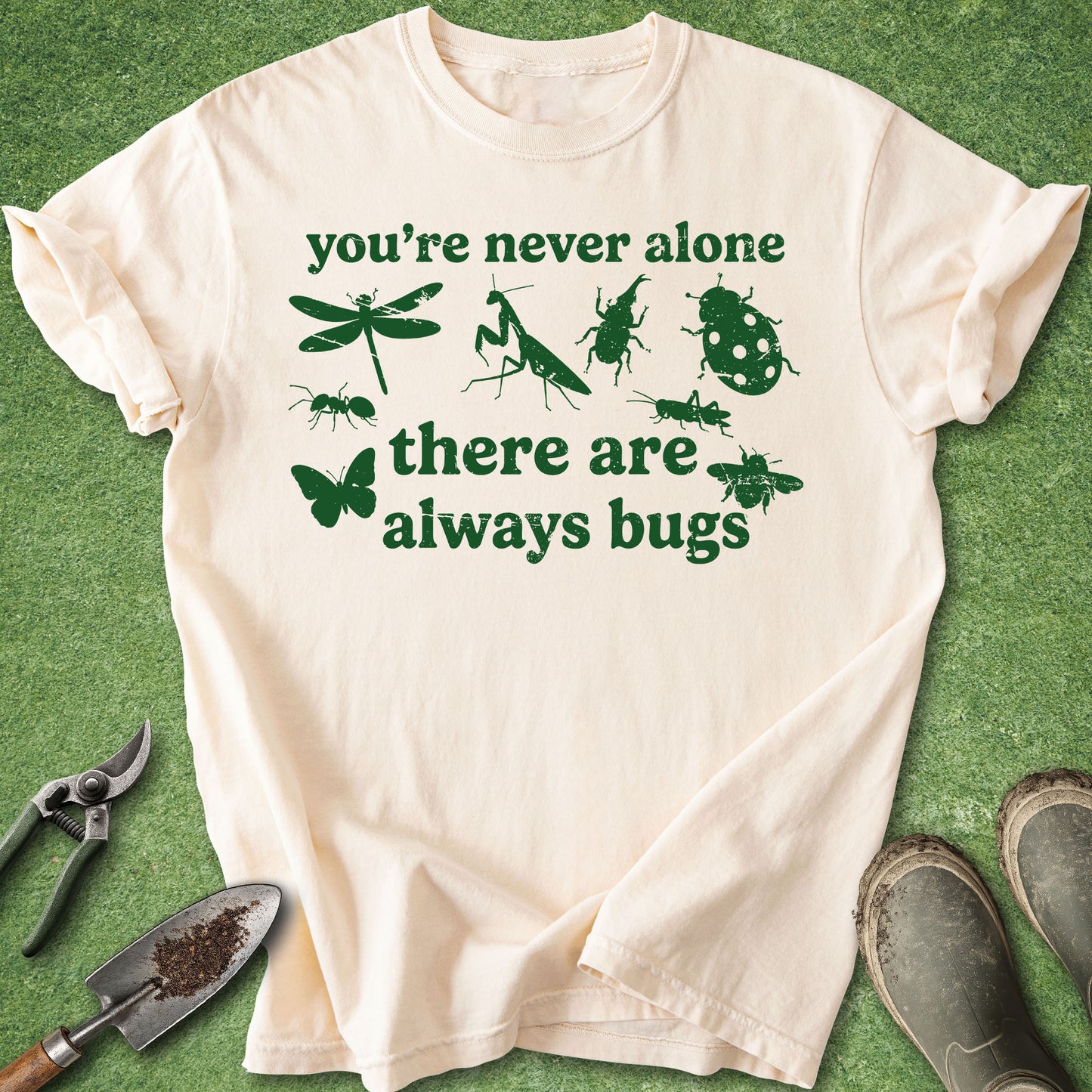 Beige t-shirt with green text and insect illustrations on a green background