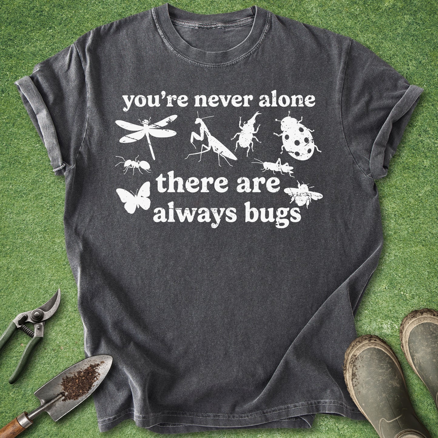 Dark gray t-shirt with white text and insect illustrations on a green grass background.