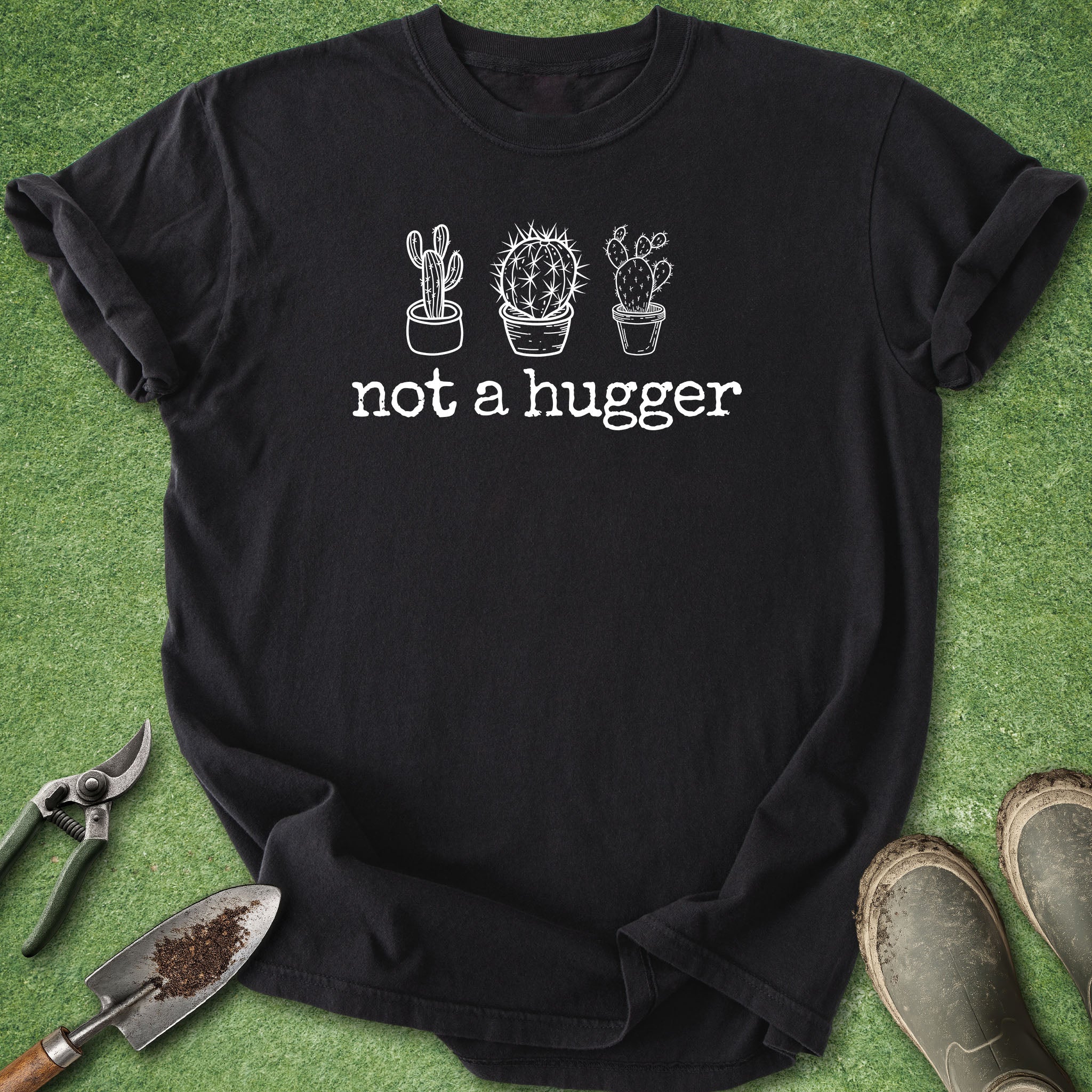 Black t-shirt with cactus design and 'not a hugger' text on a green grass background