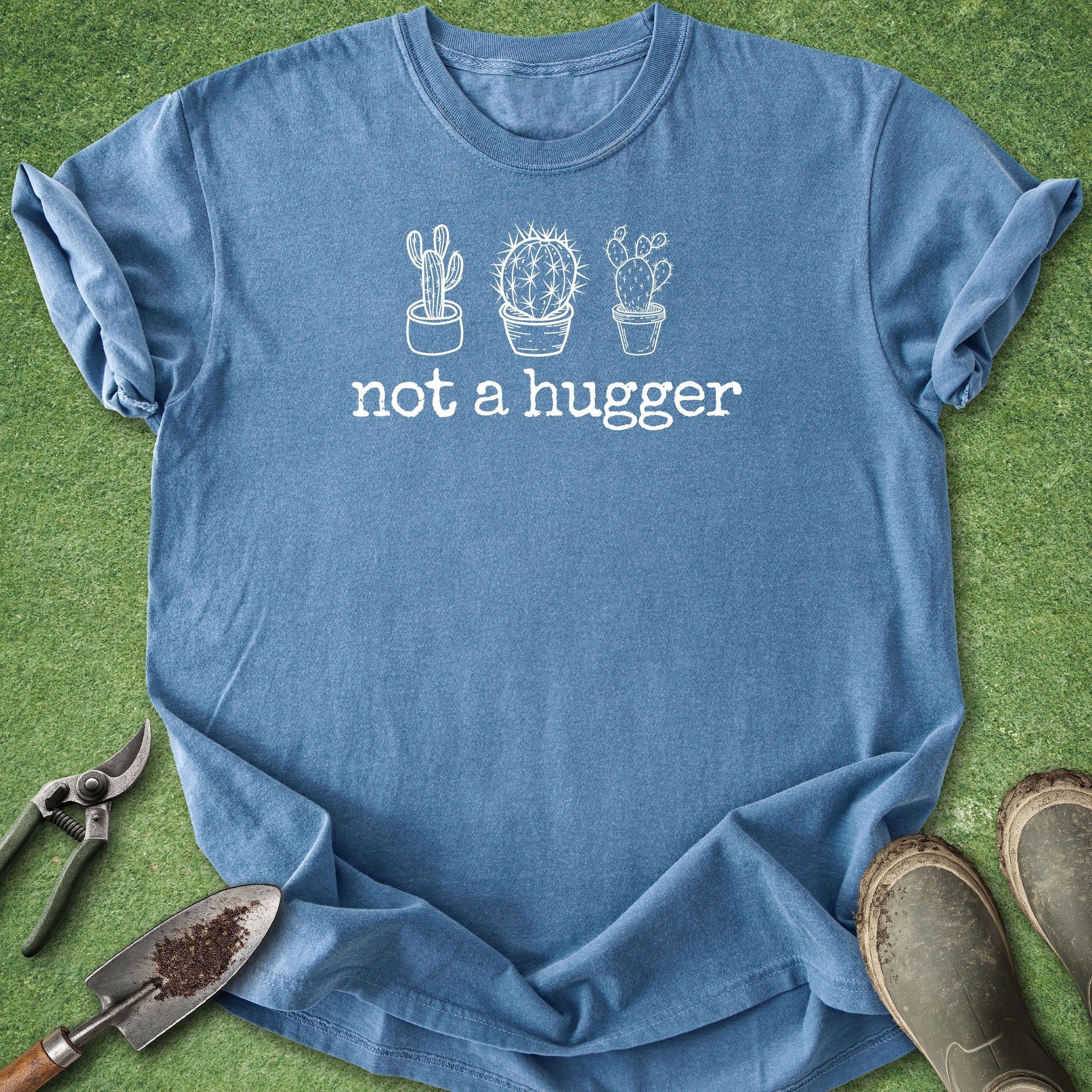 Blue t-shirt with cactus design and 'not a hugger' text on a grass background
