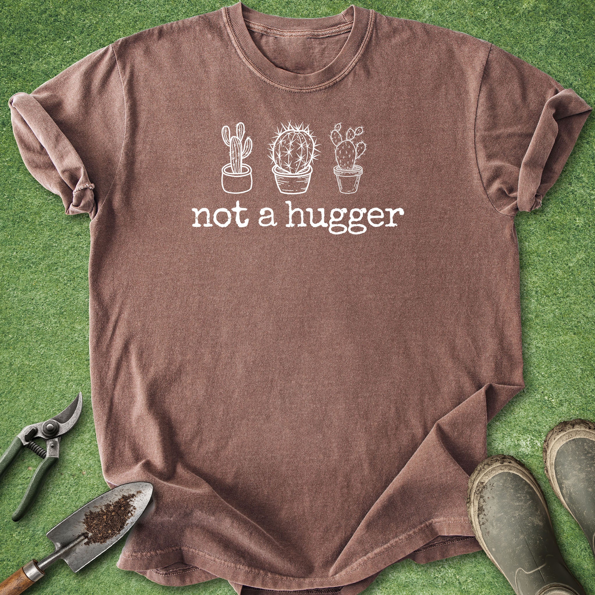 Brown t-shirt with cactus design and 'not a hugger' text on a green grass background