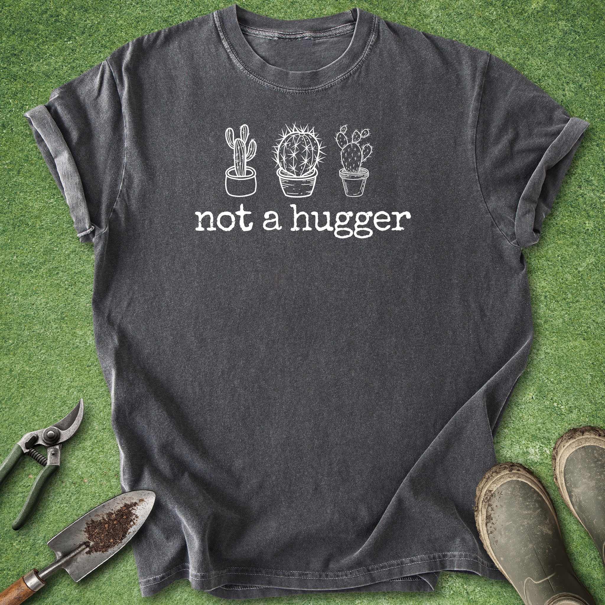Dark gray t-shirt with cactus graphic and 'not a hugger' text on a grass background