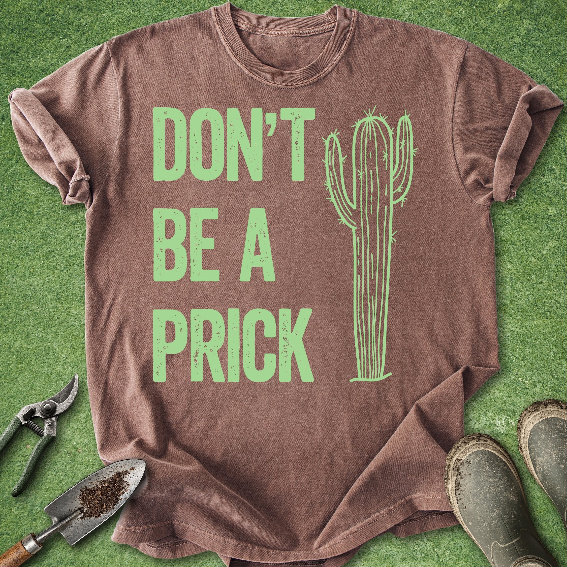 Brown t-shirt with green cactus graphic and text on a grass background