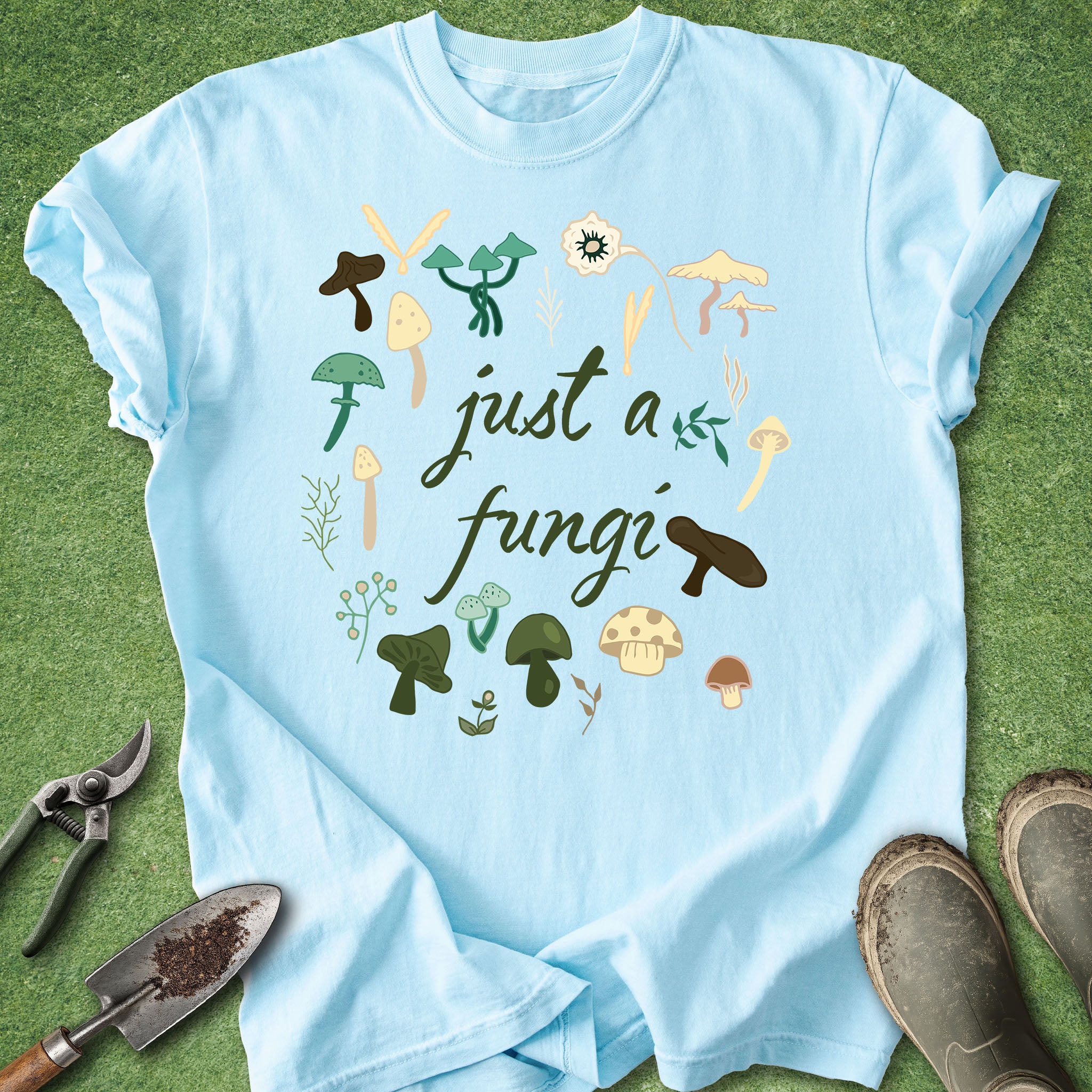 Light blue t-shirt with mushroom graphics and 'just a fungi' text on a grass background
