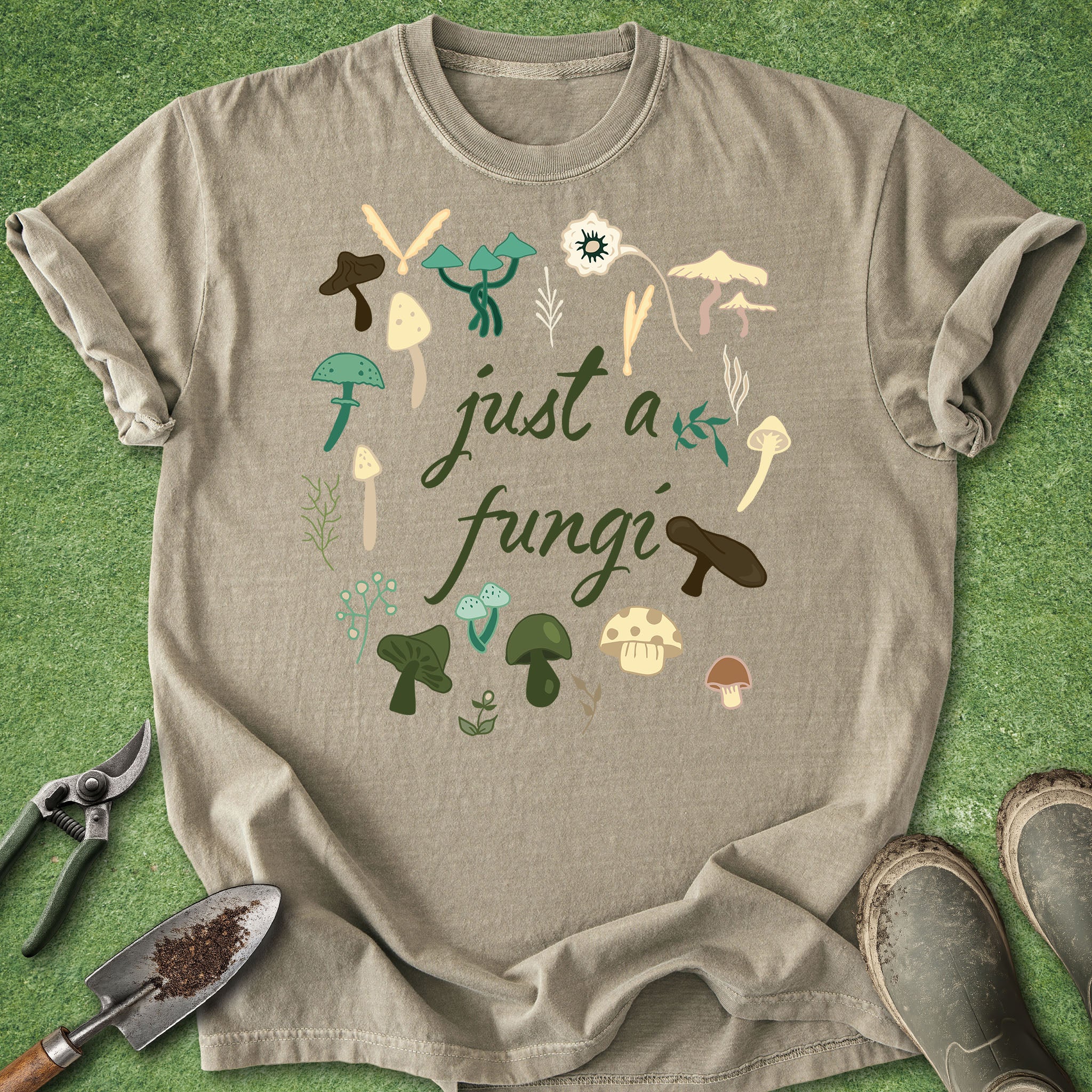 Beige t-shirt with mushroom design and text 'just a fungi' on a green grass background