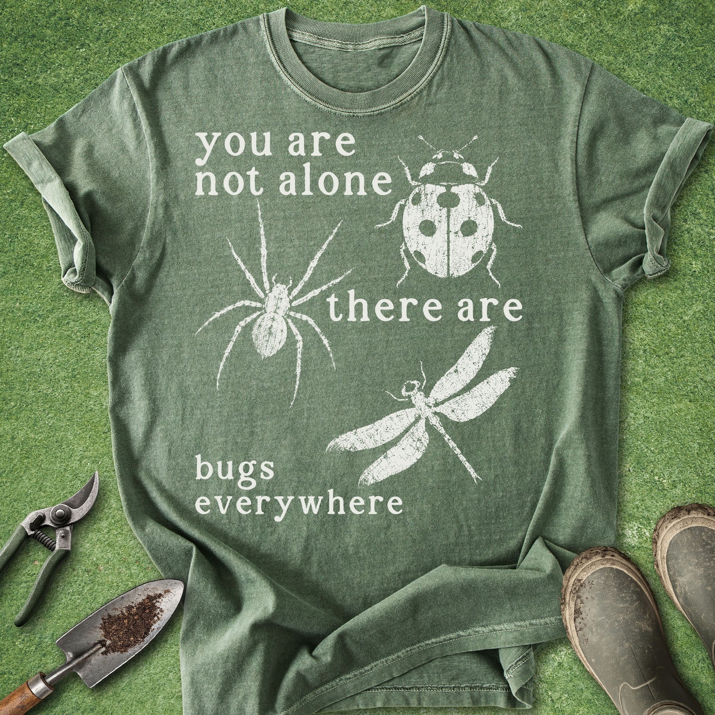 Green t-shirt with white text and insect illustrations on a grass background