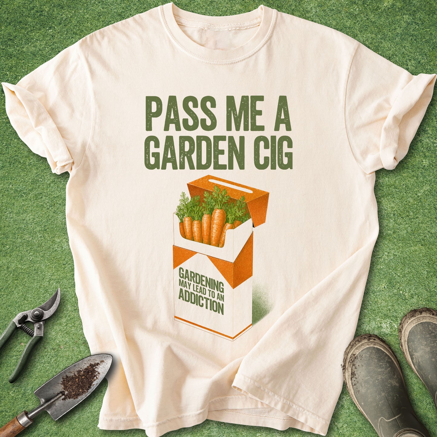 Comfort Colors Ivory t-shirt featuring the phrase "Pass Me a Garden Cig" above a humorous carrot cigarette pack illustration with the warning "Gardening May Lead To An Addiction."