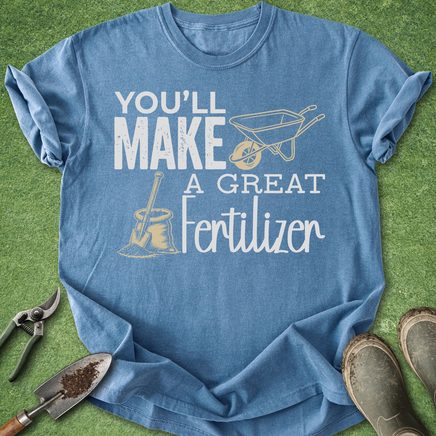 Blue t-shirt with gardening-themed text and graphics on a grass background