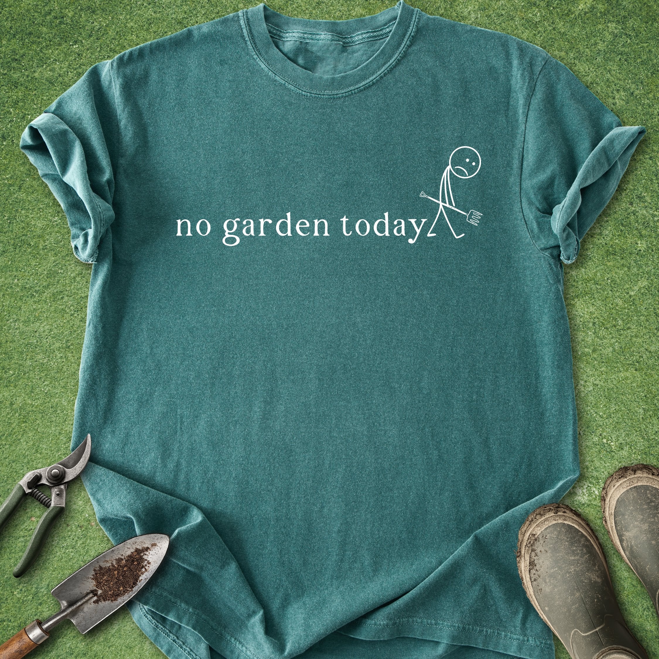 Teal t-shirt with 'no garden today' text and gardening tools on a grass background