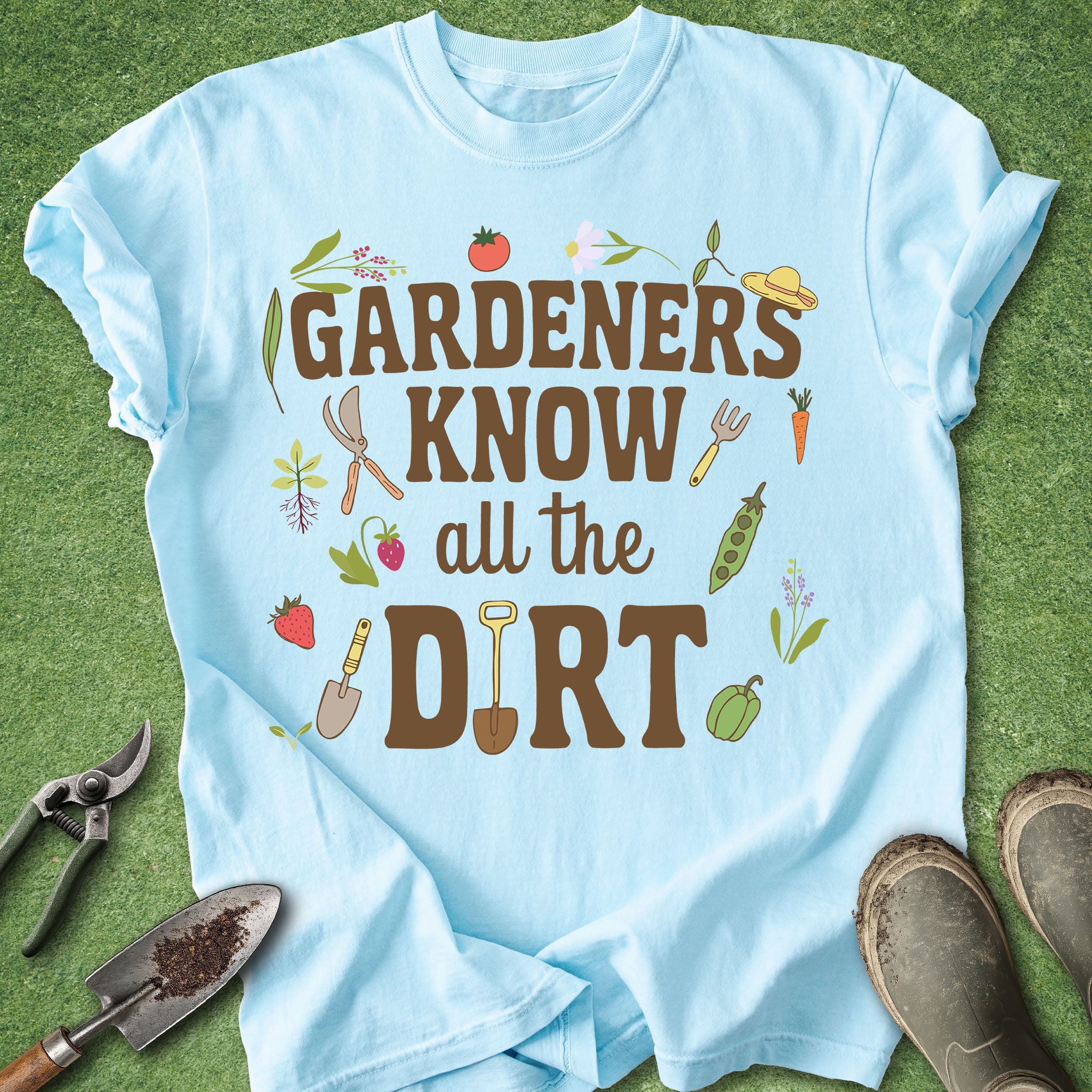 Light blue t-shirt with gardening-themed text and graphics on a grass background